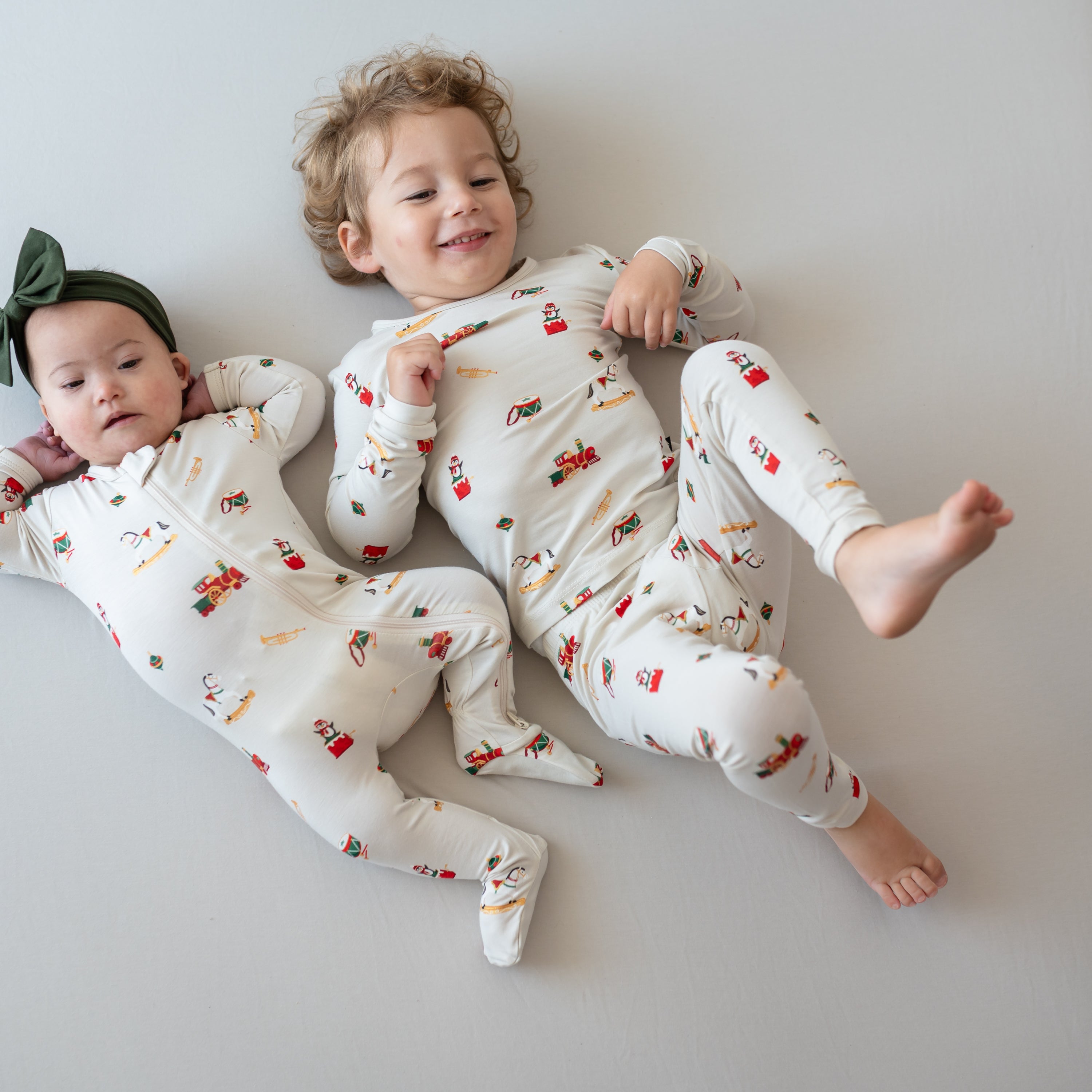 Brother and sister laying on a bed side by side matching in Vintage Toys pajamas