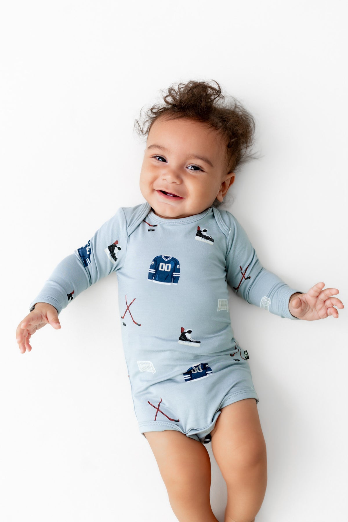 Baby smiling in Long Sleeve Bodysuit in Vintage Hockey print on a white background
