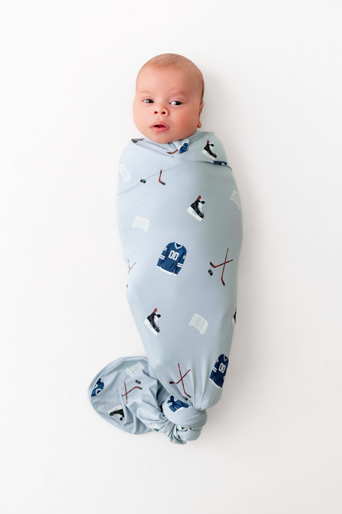 Baby wrapped in Swaddle Blanket in Vintage Hockey print on a white background