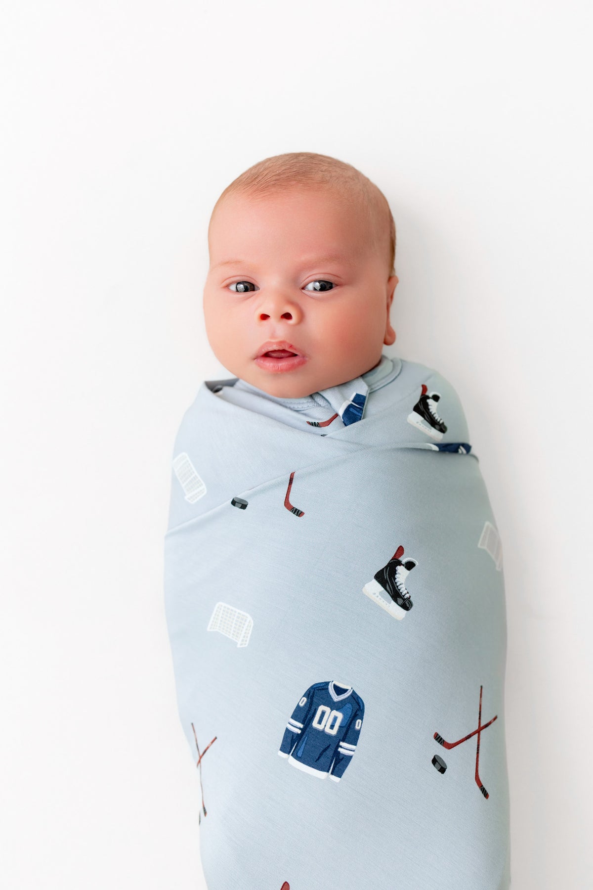 Close up of Baby wrapped in Swaddle Blanket in Vintage Hockey print on a white background