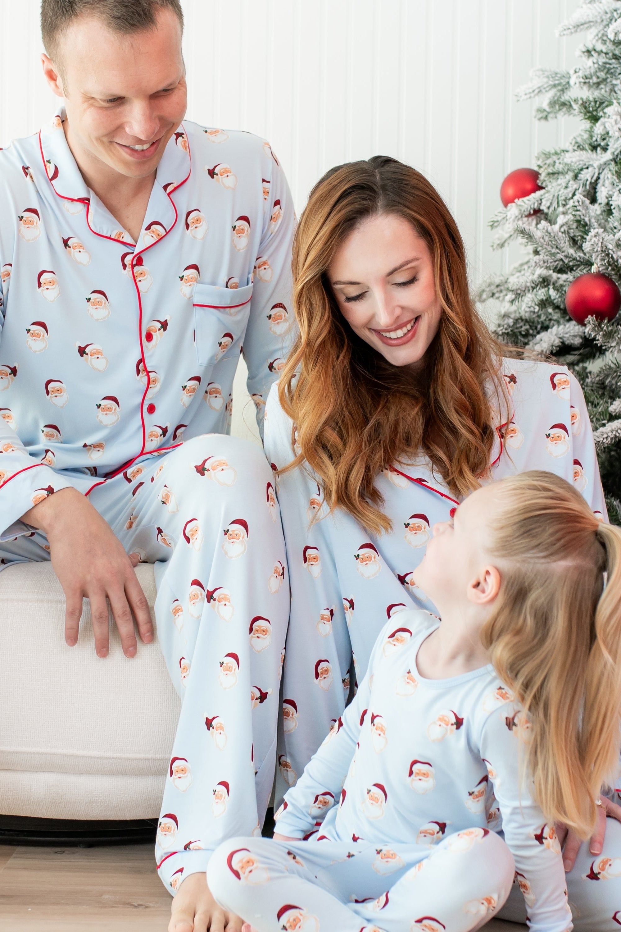 Family of 3 sitting around one another matching in Vintage Santa Pajamas