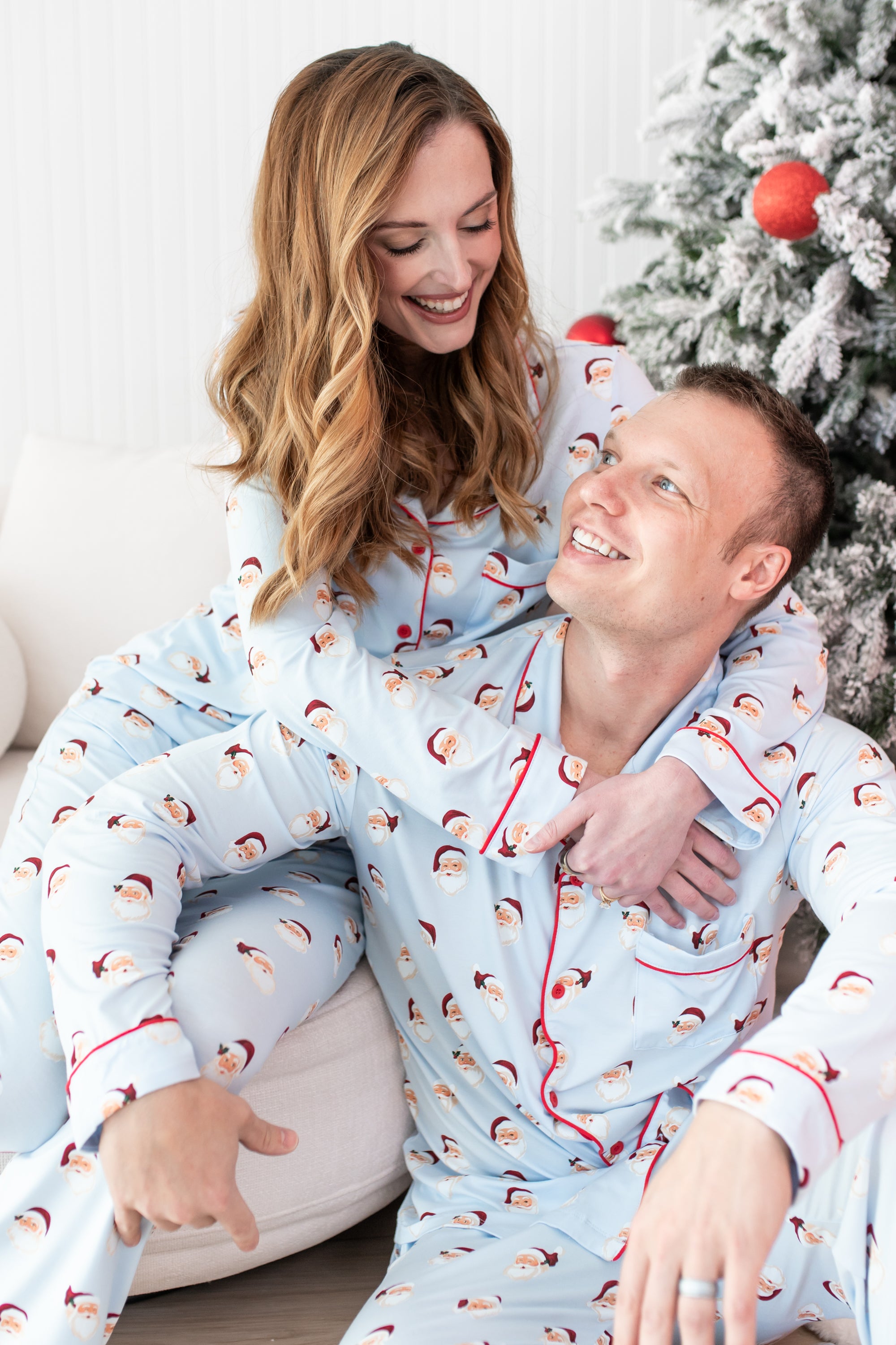 Husband and wife sitting beside each other matching in the Men's and Long-Sleeved Women's Pajama Set in Vintage Santa