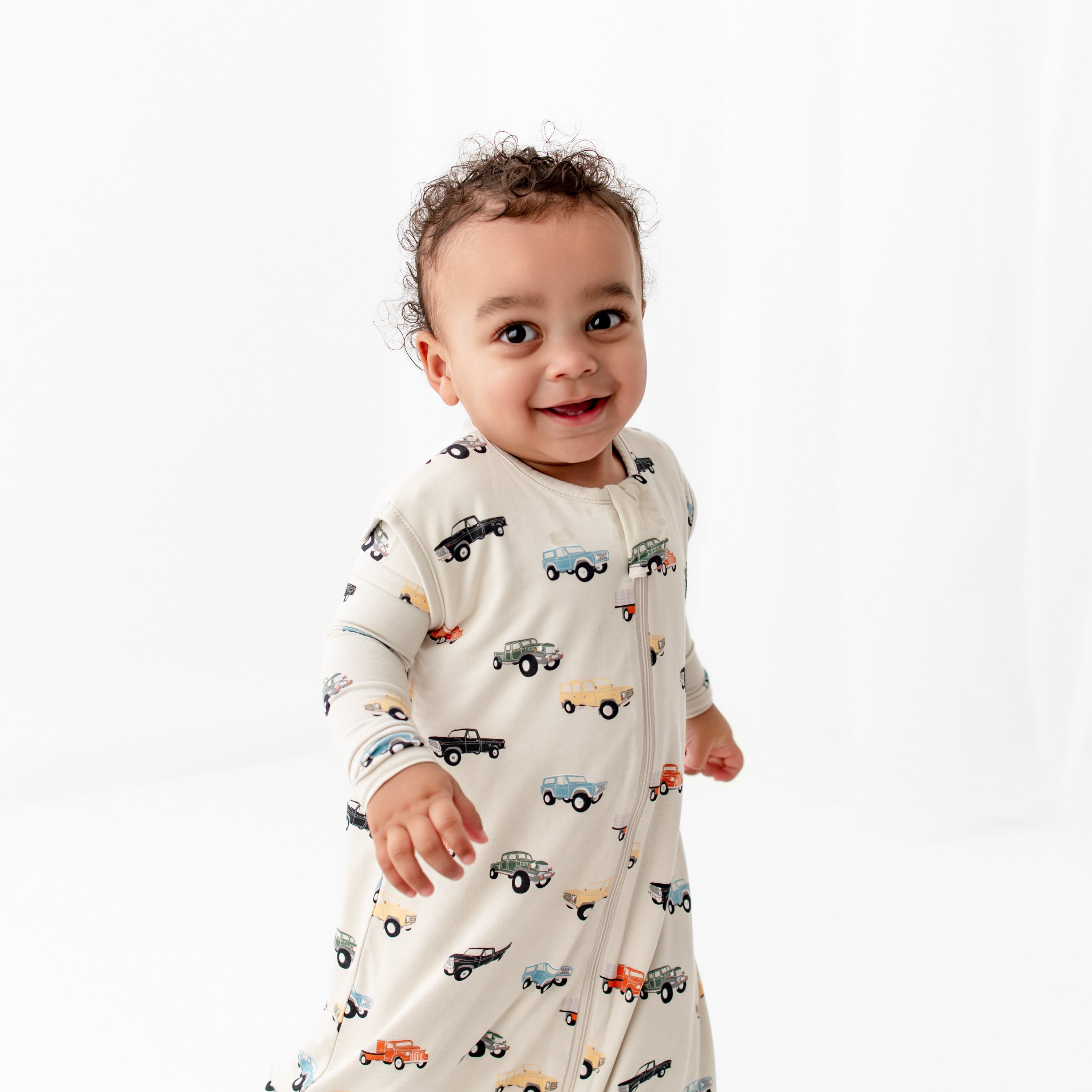 Smiling child model wearing the Sleep Bag Walker in Vintage Truck 0.5