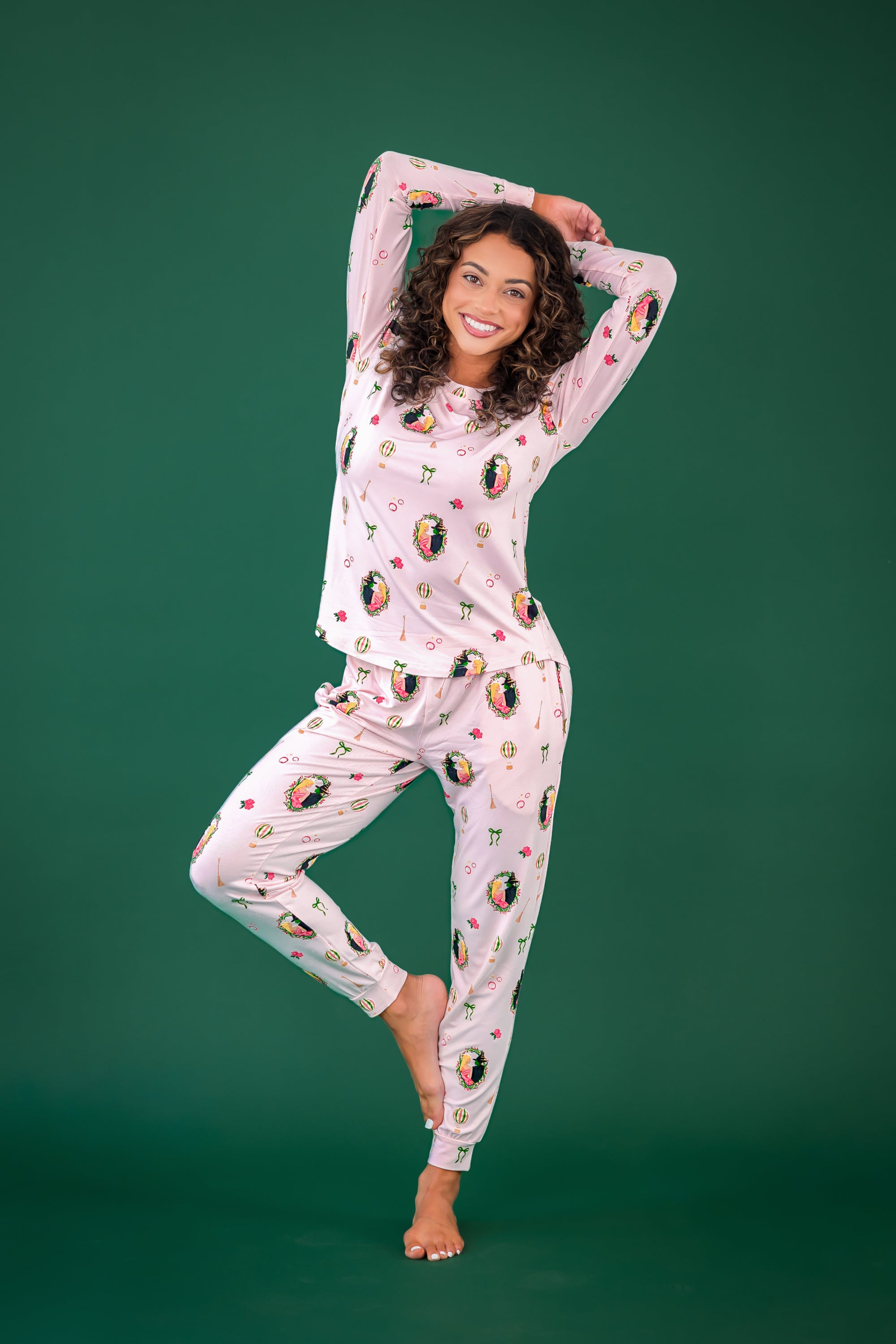 Female posing wearing the Women's Jogger Pajama Set in Wicked in front of a forest green background