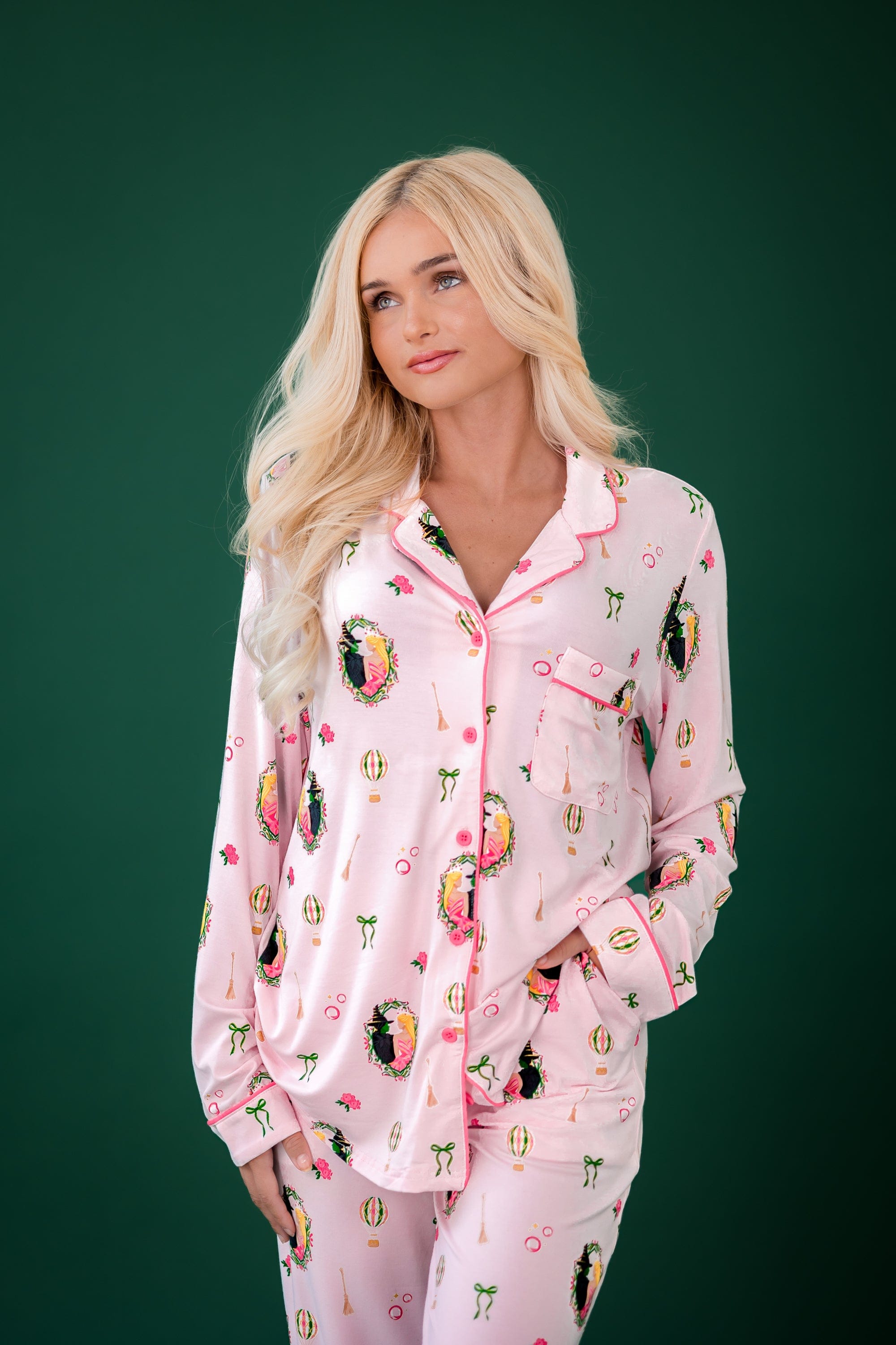 Female model standing in front of a forest green background wearing the Long-Sleeved Women's Pajama Set in Wicked with one hand in the pants pocket