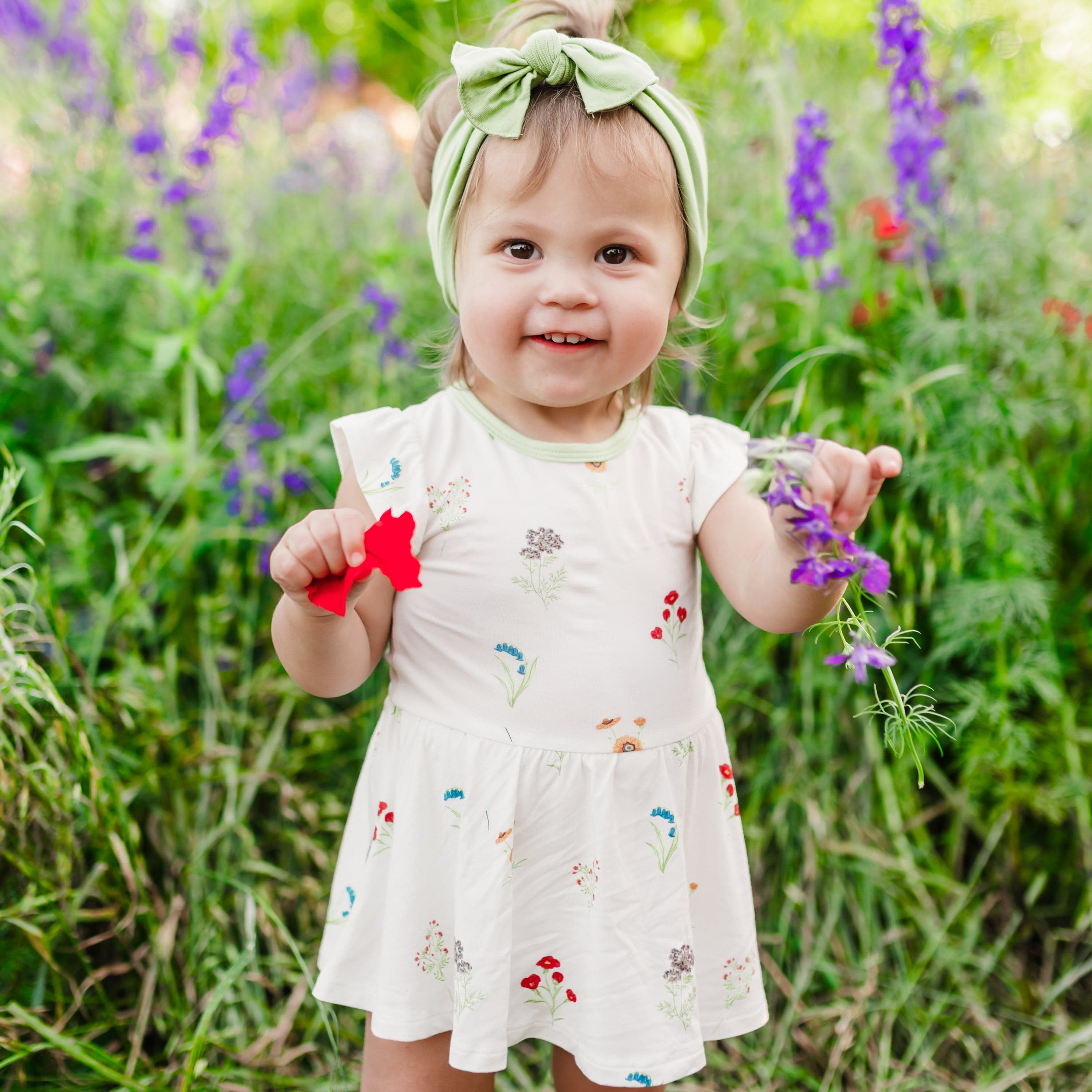 Toddler wearing Twirl Bodysuit Dress in Wildflower in a field of flowers