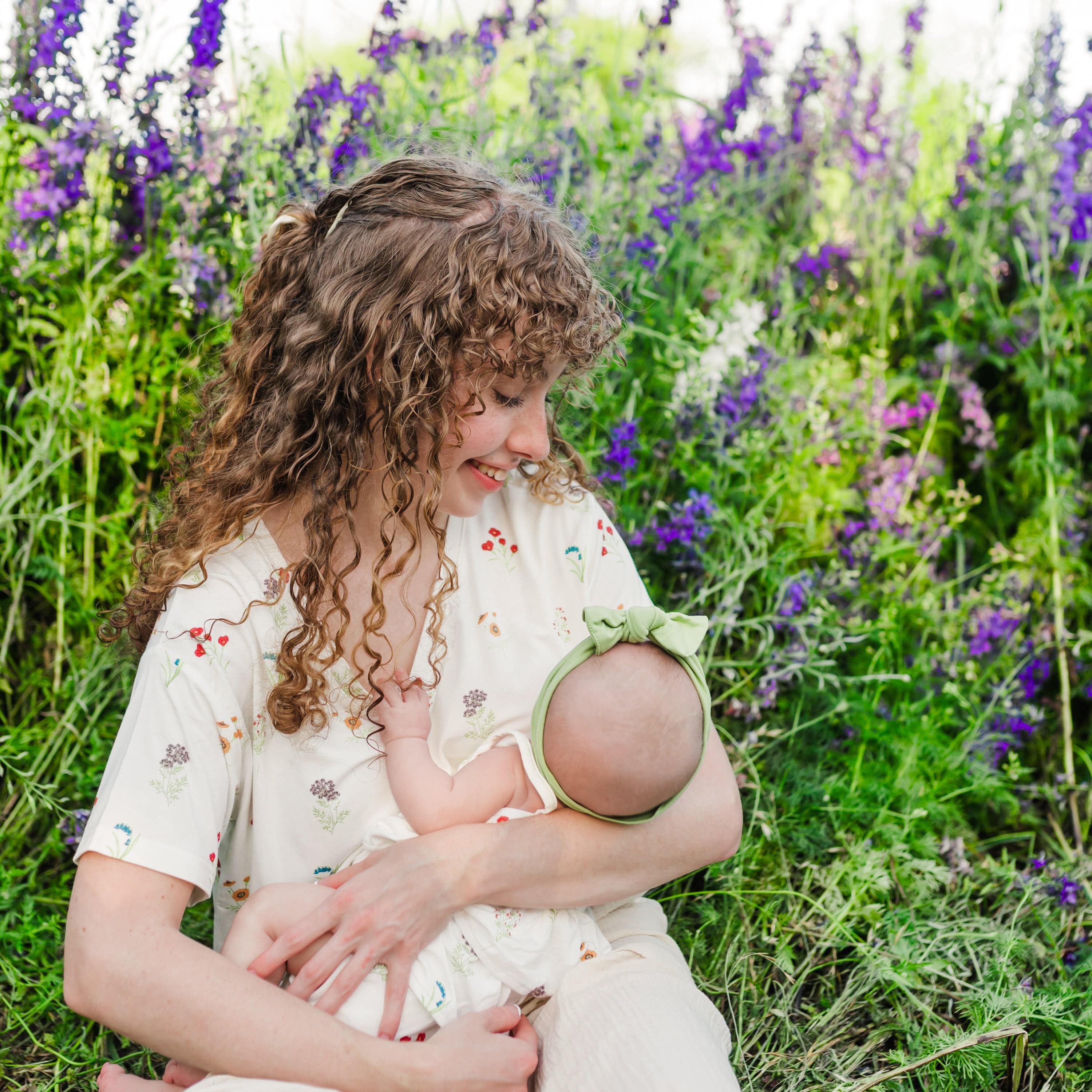 Woman wearing Women’s Relaxed Fit V-Neck in Wildflower holding baby in a wildflower field