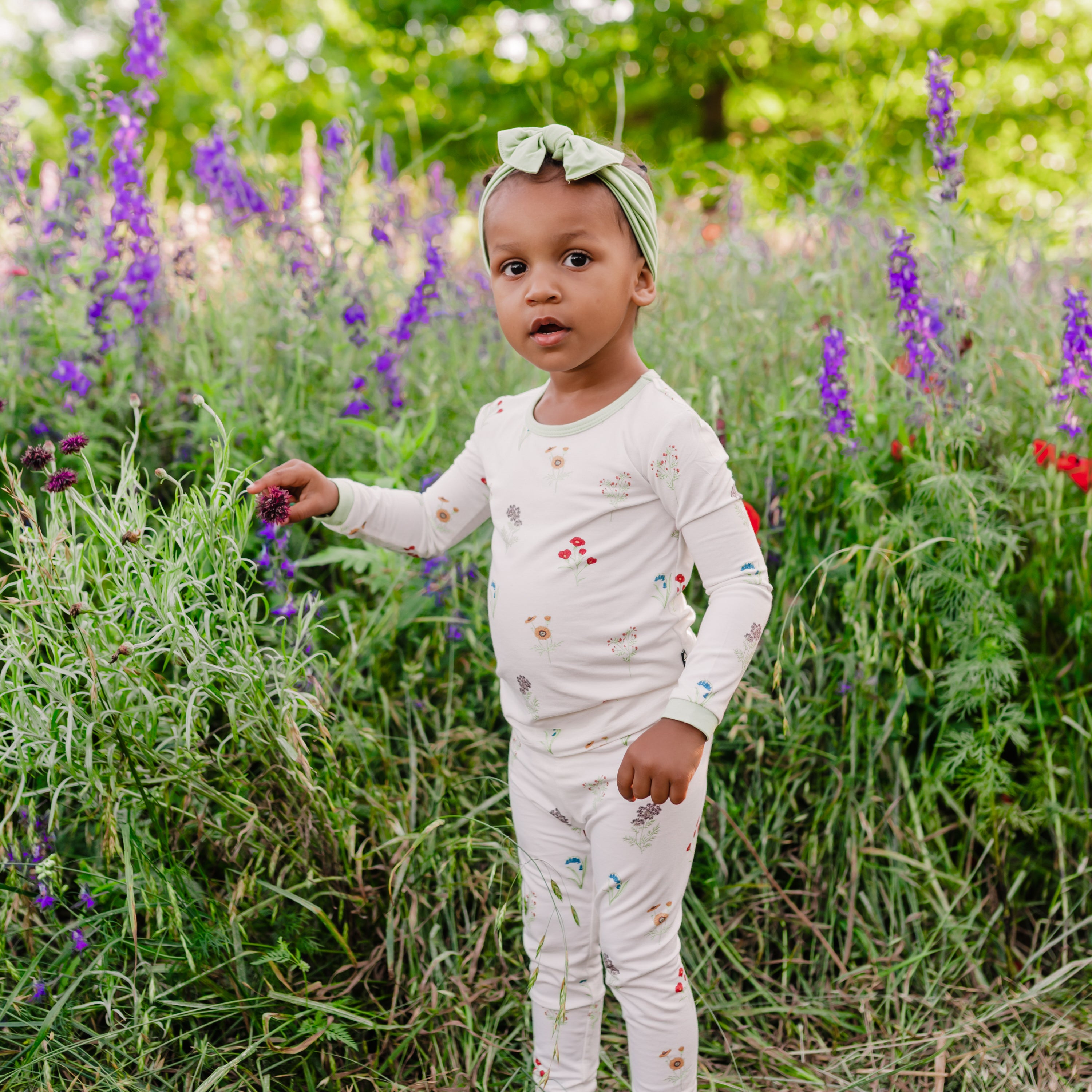 Toddler modeling Long Sleeve Pajamas in Wildflower in a wildflower field