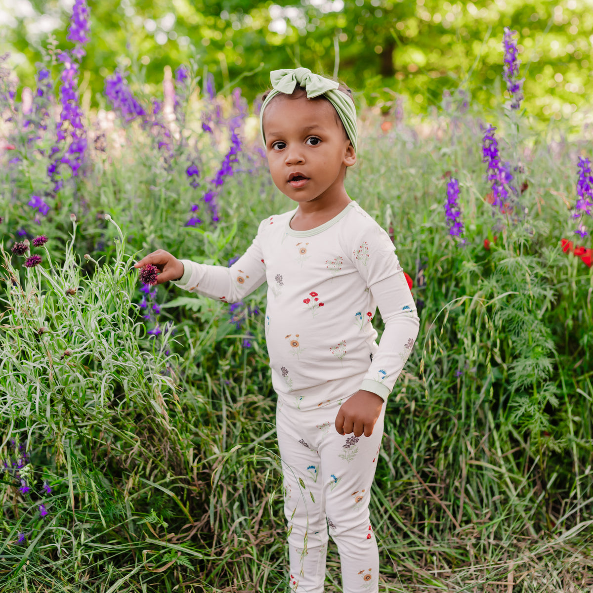 Toddler modeling Long Sleeve Pajamas in Wildflower in a wildflower field