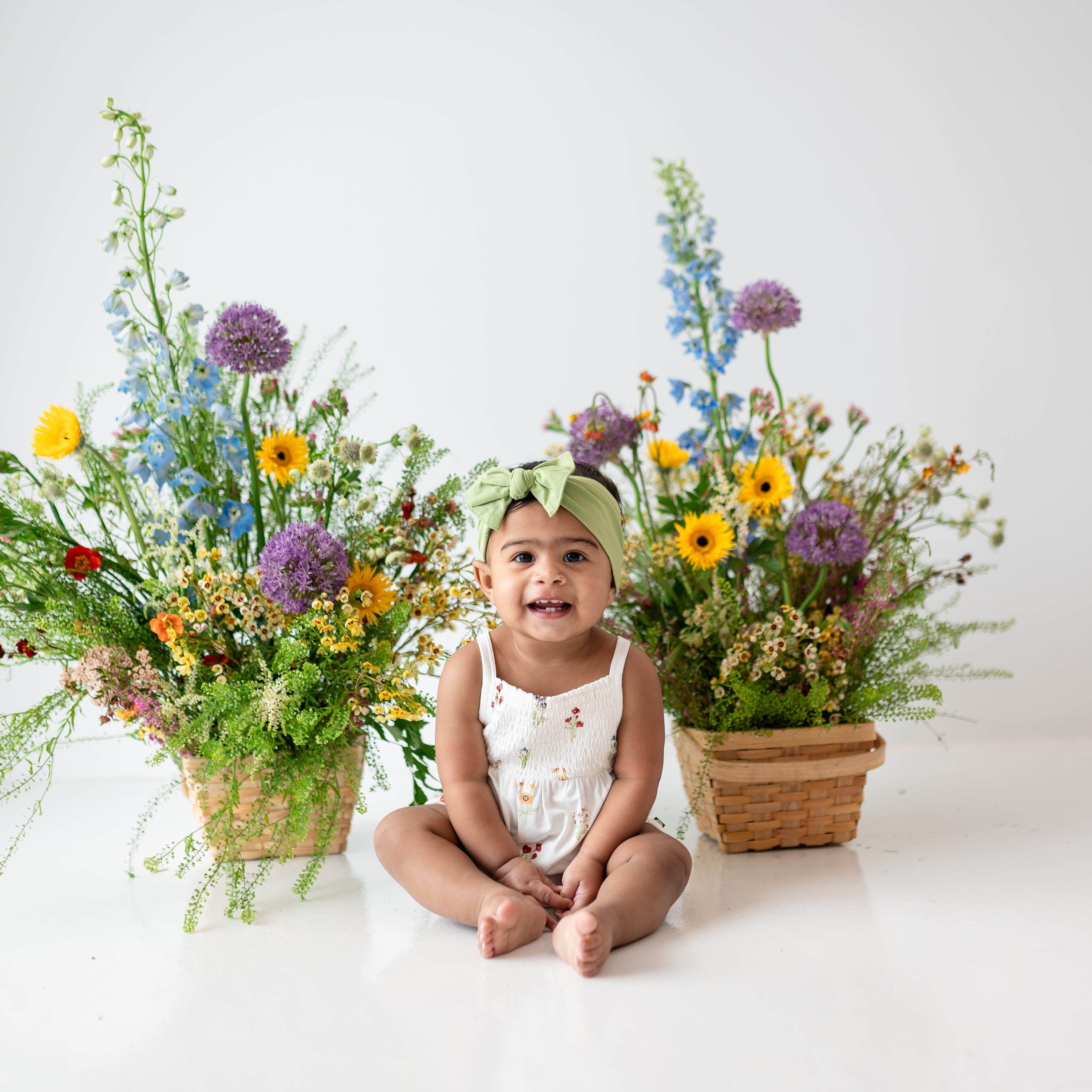 Young toddler sitting and wearing Smocked Bubble Romper in Wildflower