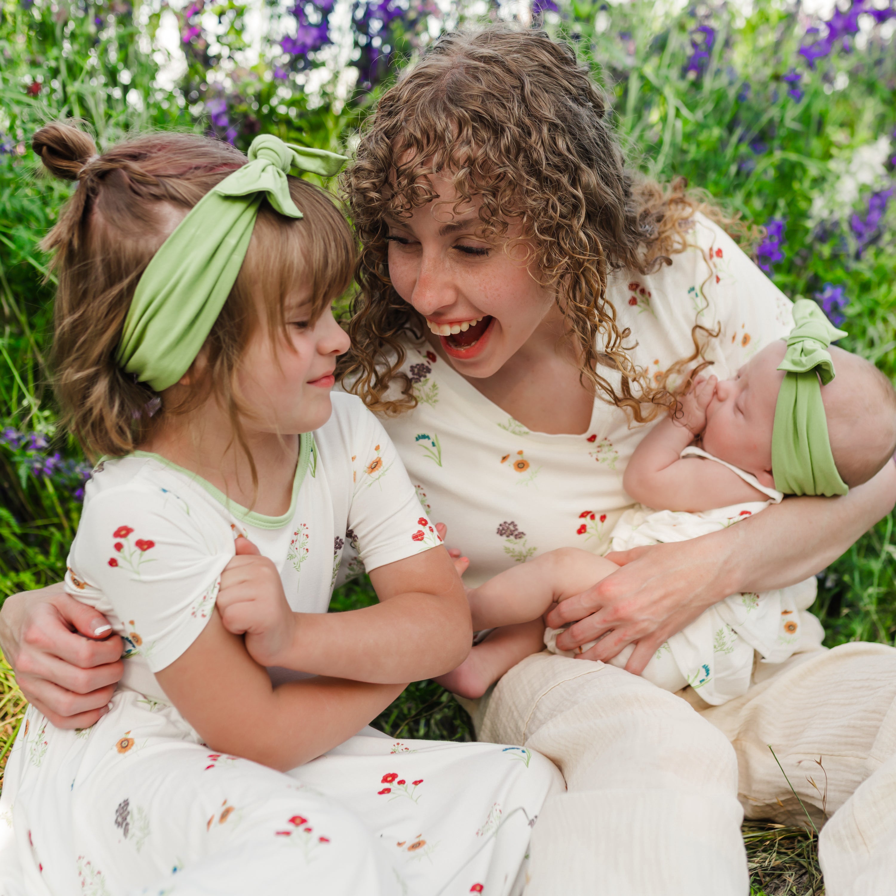 Woman wearing Women’s Relaxed Fit V-Neck in Wildflower holding baby and toddler in a wildflower field