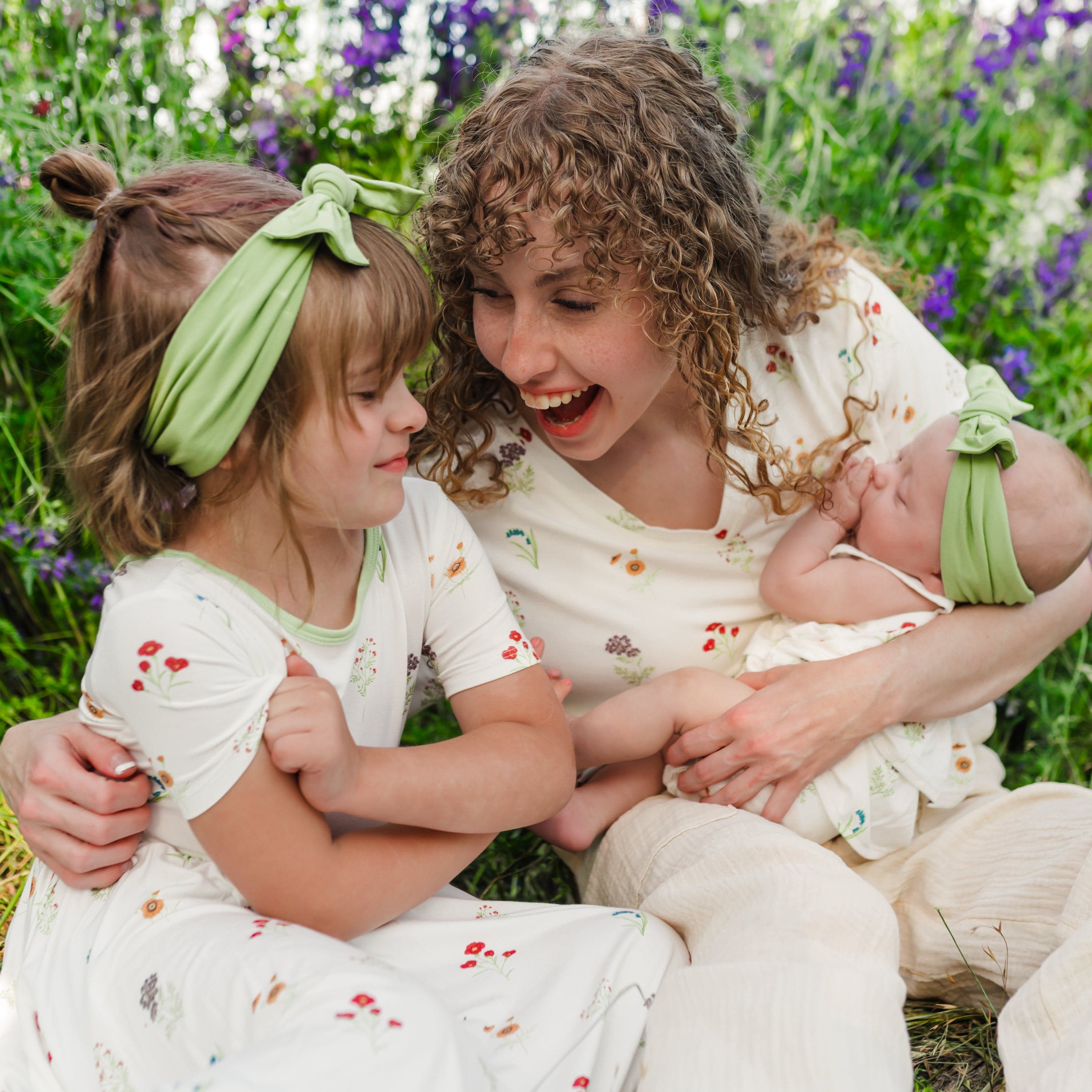 Woman wearing Women’s Relaxed Fit V-Neck in Wildflower holding baby and toddler in a wildflower field