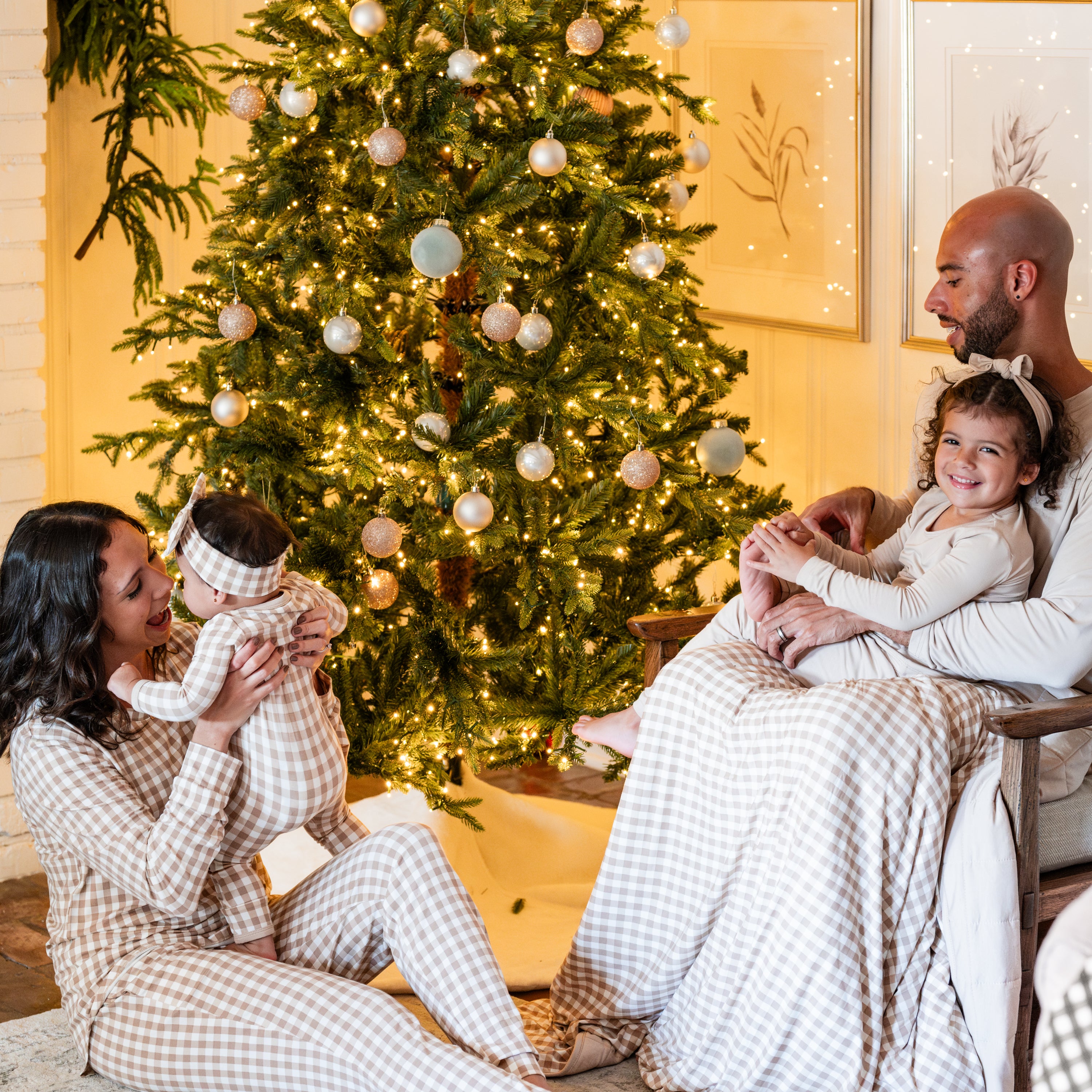 Family wearing matching holiday pajamas in Gingham Bisque and solid Bisque wrapped in soft Youth Blanket