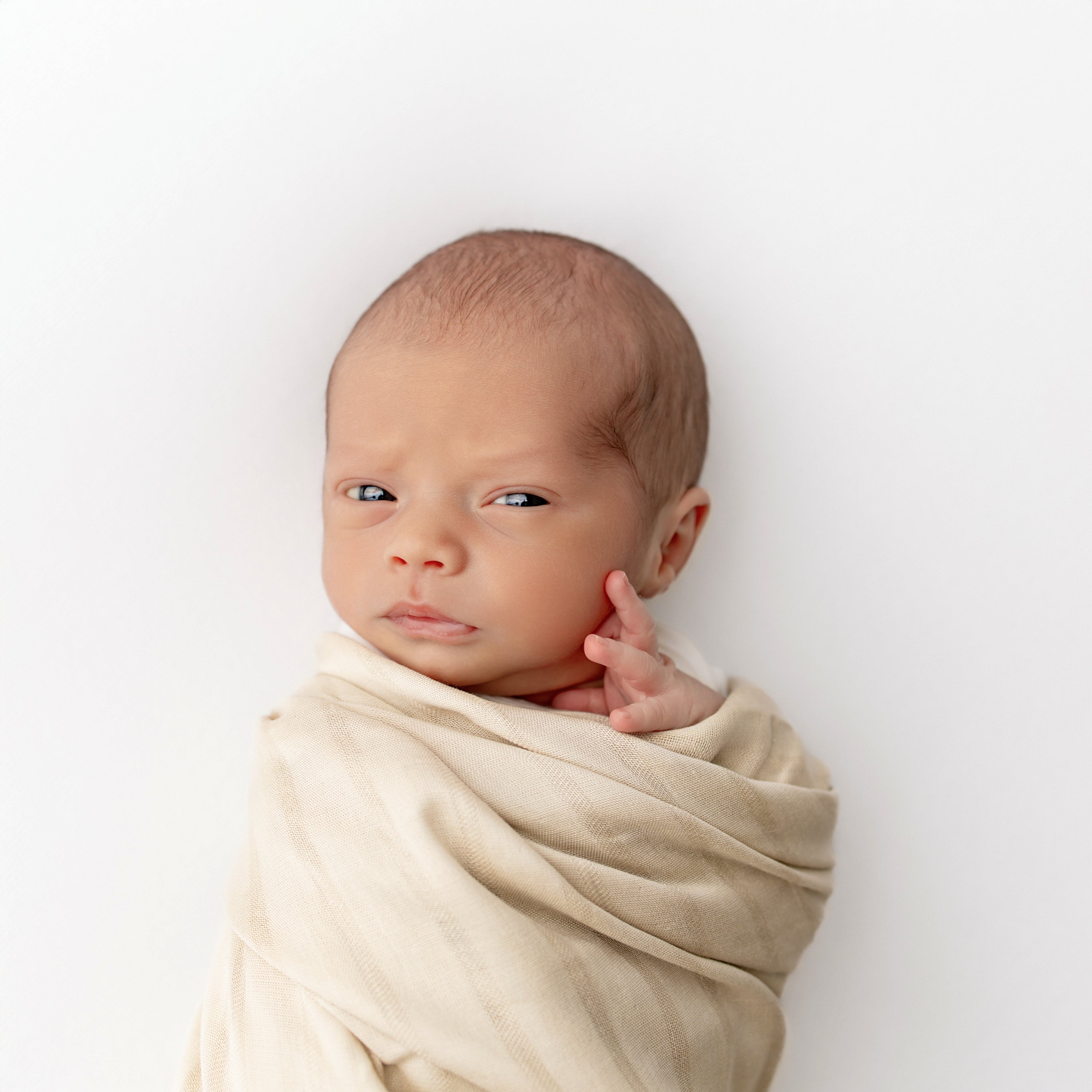Newborn wrapped in Bamboo Muslin Swaddle Blanket in Wheat with Woven Striped Detail