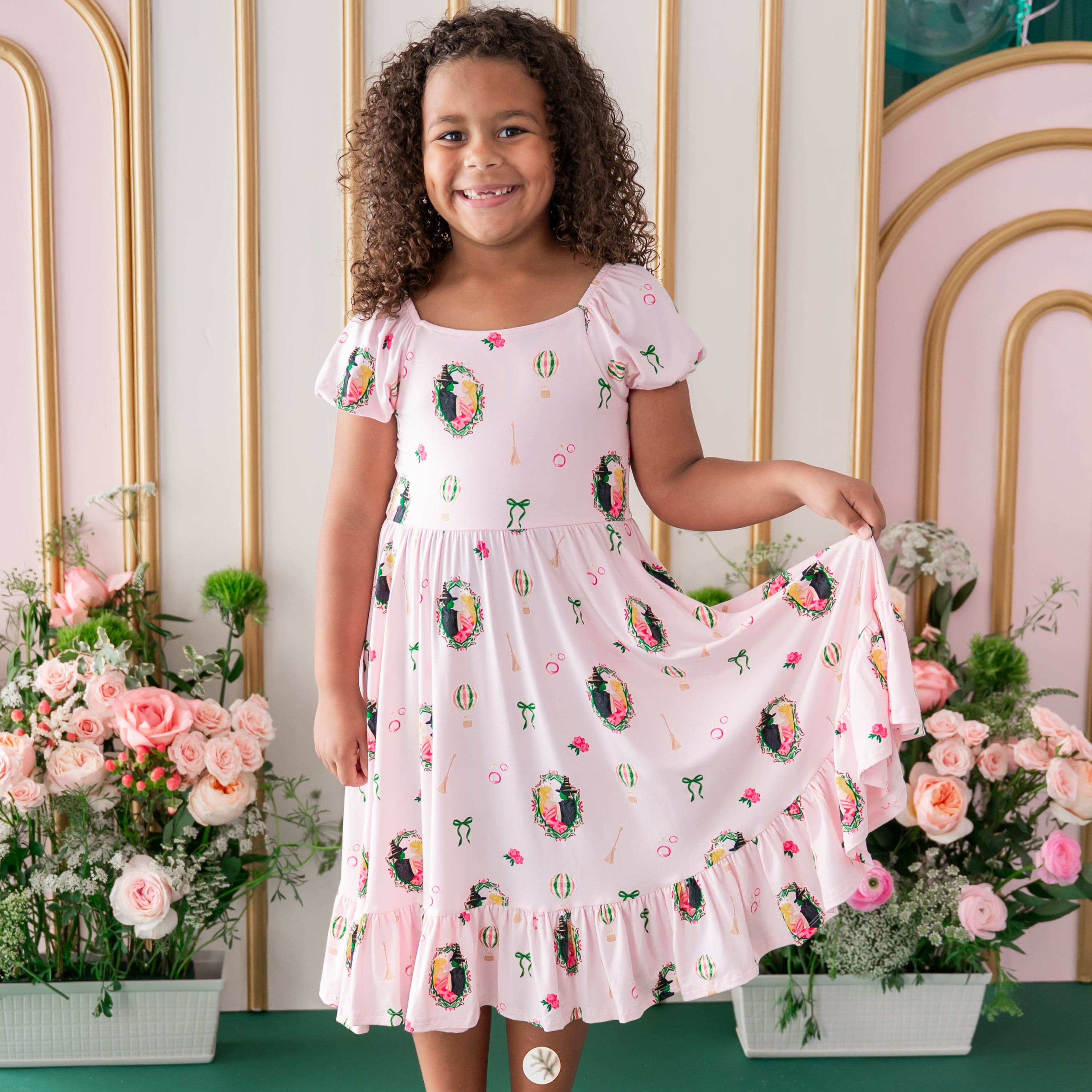 Young girl standing in front of a floral backdrop wearing the Puff Sleeve Twirl Dress in Wicked