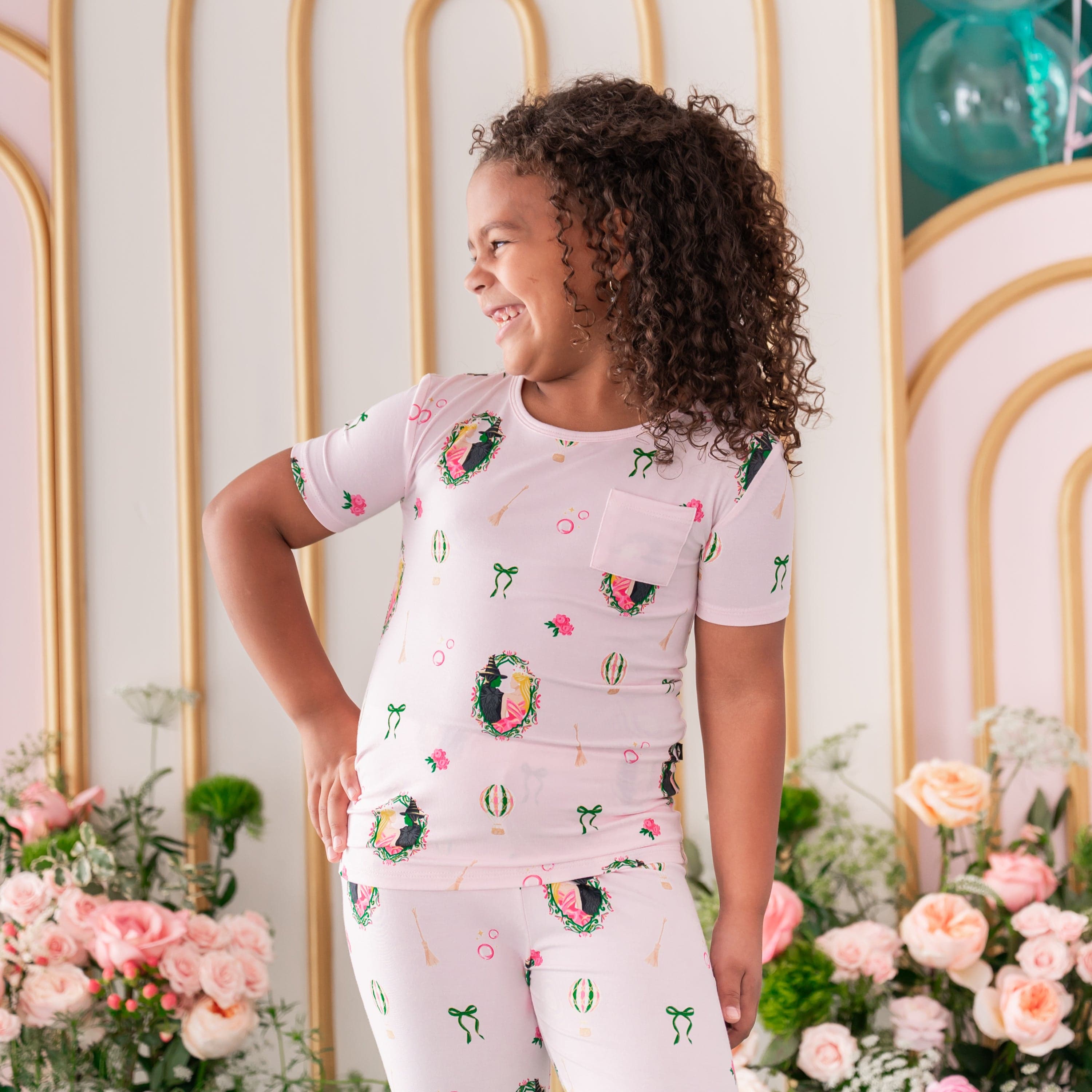 Smiling girl wearing the Short Sleeve with Pants Pajamas in Wicked standing with one hand on her hip looking off to the side