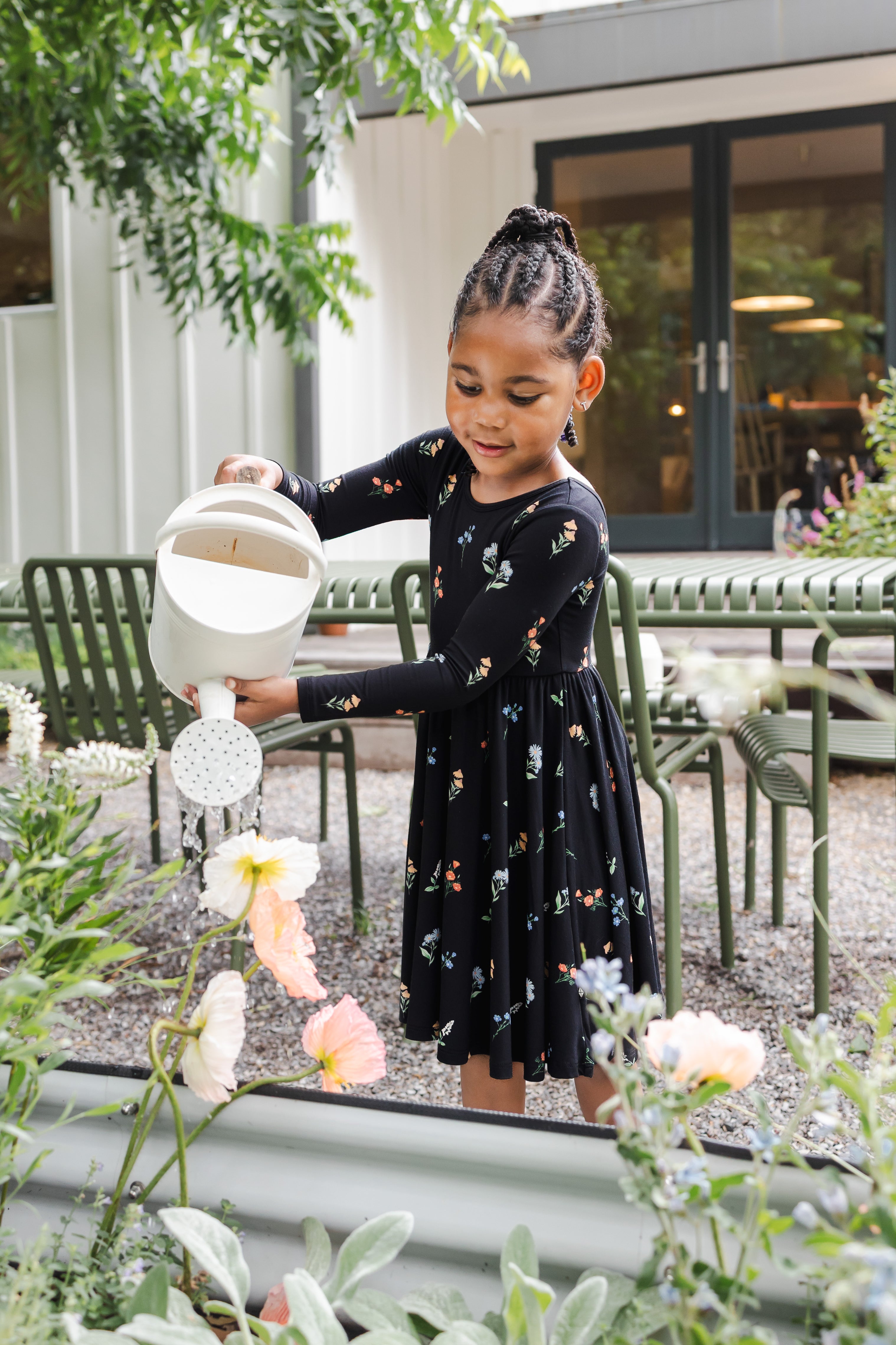 Girl watering the plants outdoors wearing Long Sleeve Twirl Dress in Midnight Wildflower print