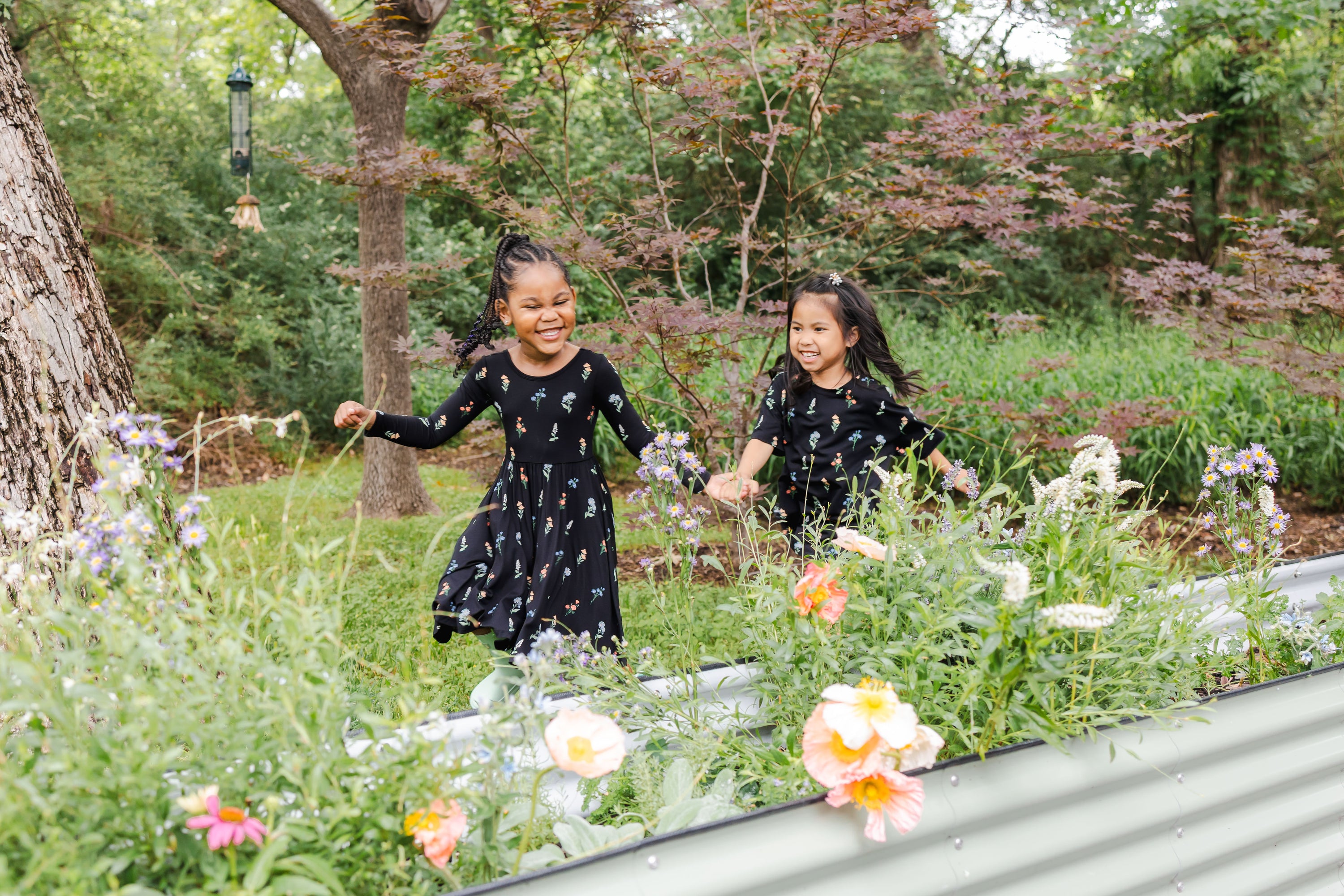 2 children running in a garden wearing black bamboo rayon outfits with a wildflower pattern