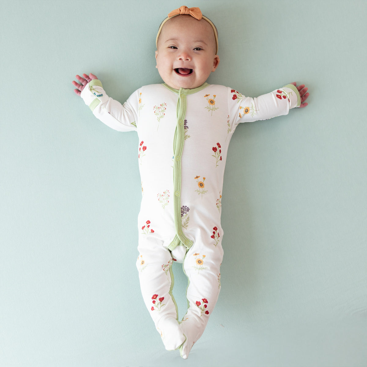 Baby smiling wearing Footie in Wildflower