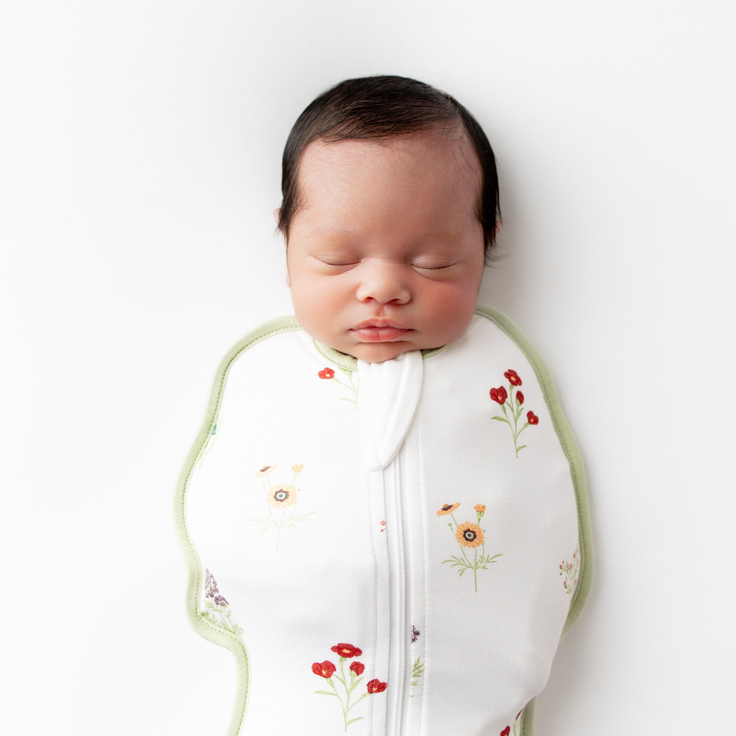 Close up of sleeping newborn wearing the Swaddle Bag in Wildflower 0.5