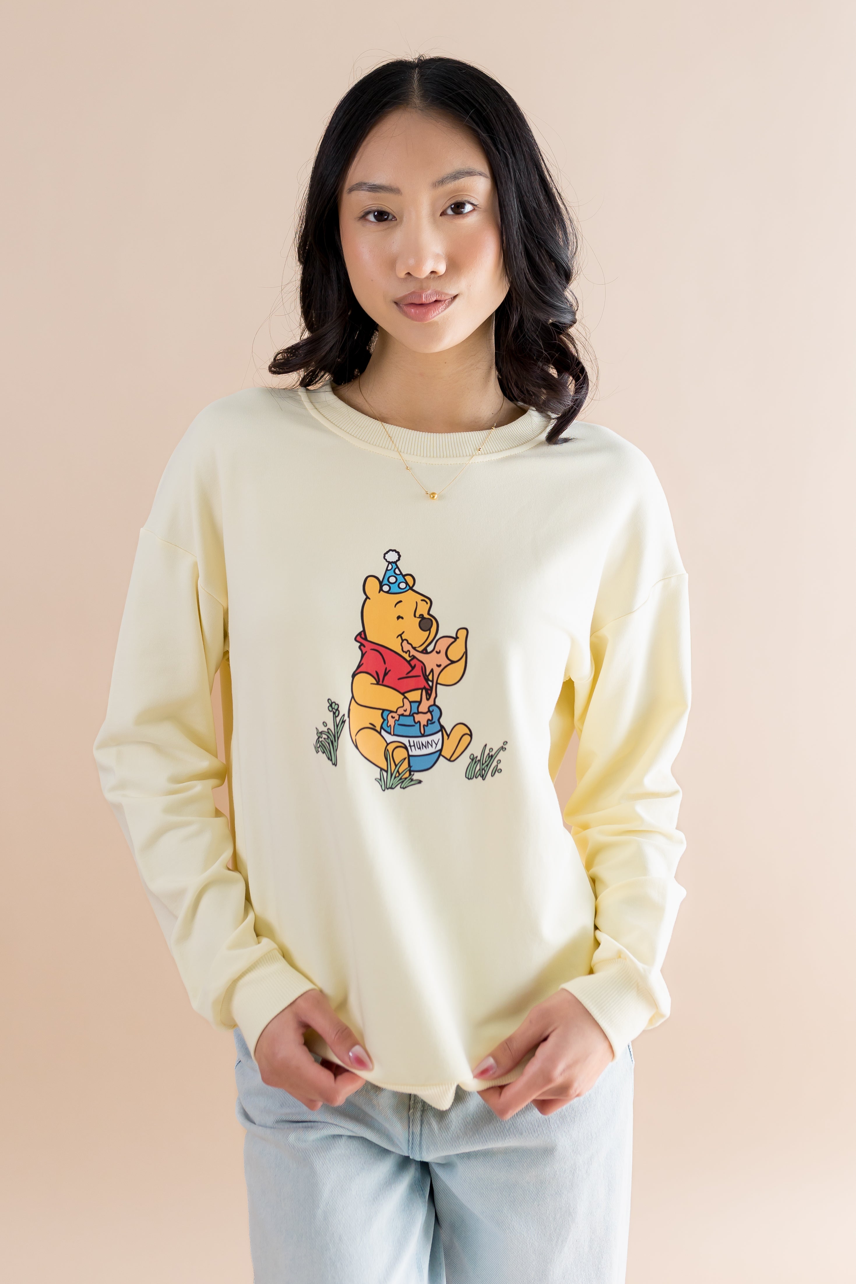 Female modeling the Women's Sweatshirt in Winnie the Pooh on Chamomile paired with light wash jeans