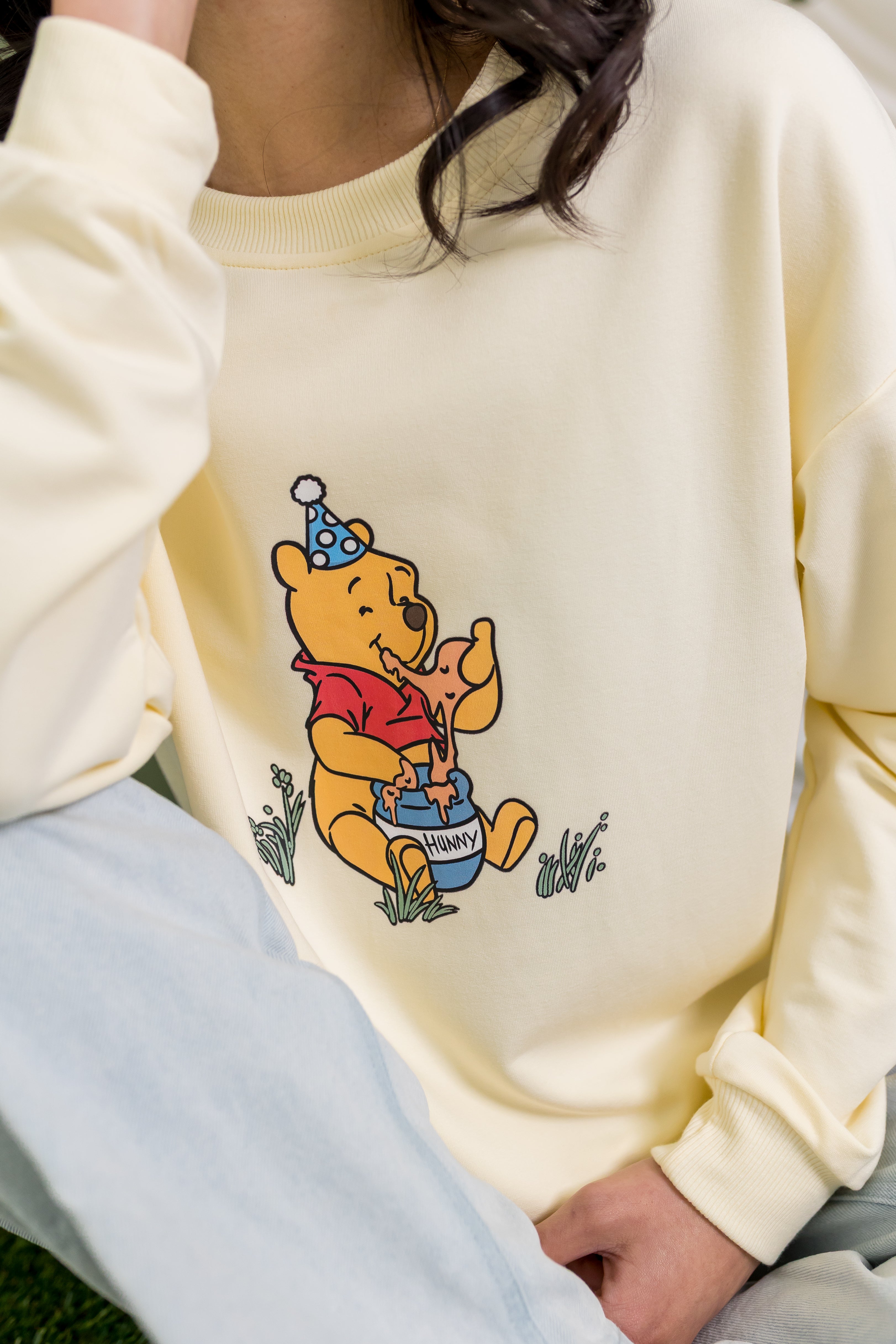 Close up of the winnie the pooh character on the Women's Sweatshirt in Winnie the Pooh on Chamomile shown on a female model