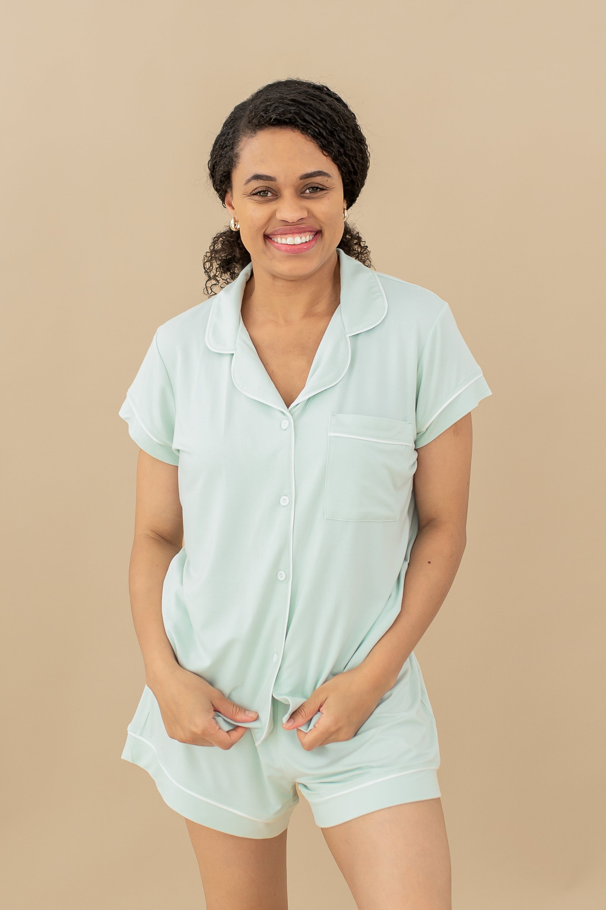 Smiling female model wearing the Women's Short Sleeve Pajama Set in Dew in front of a light taupe background
