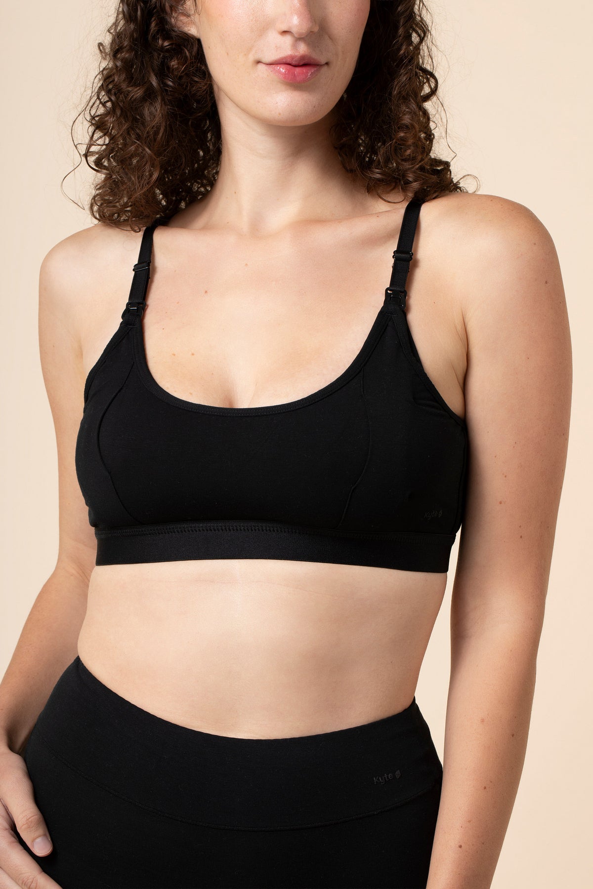 Woman wearing a black pumping bra and leggings on a beige background