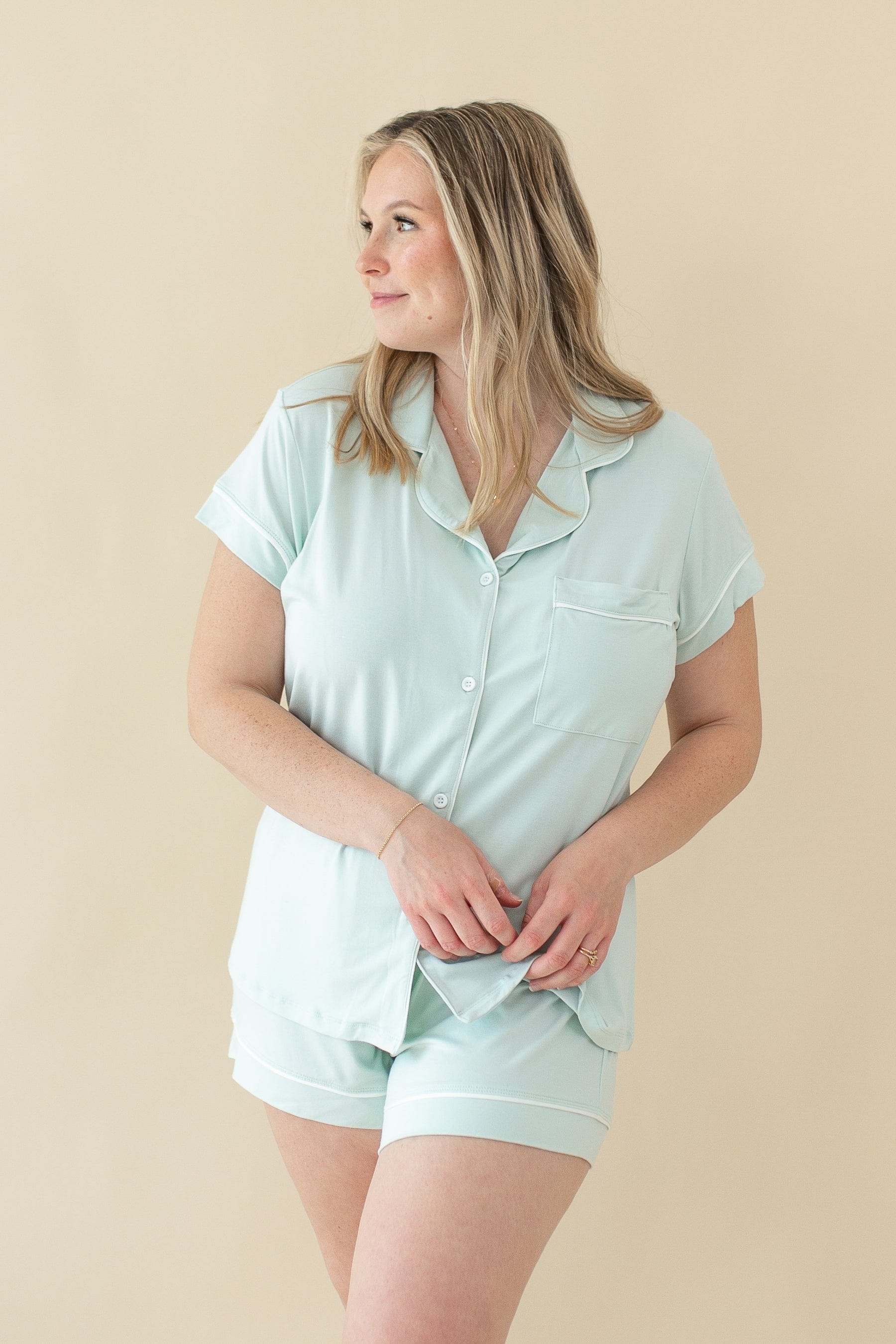 Female modeling the Women's Short Sleeve Pajama Set in Dew standing in front of a light taupe background