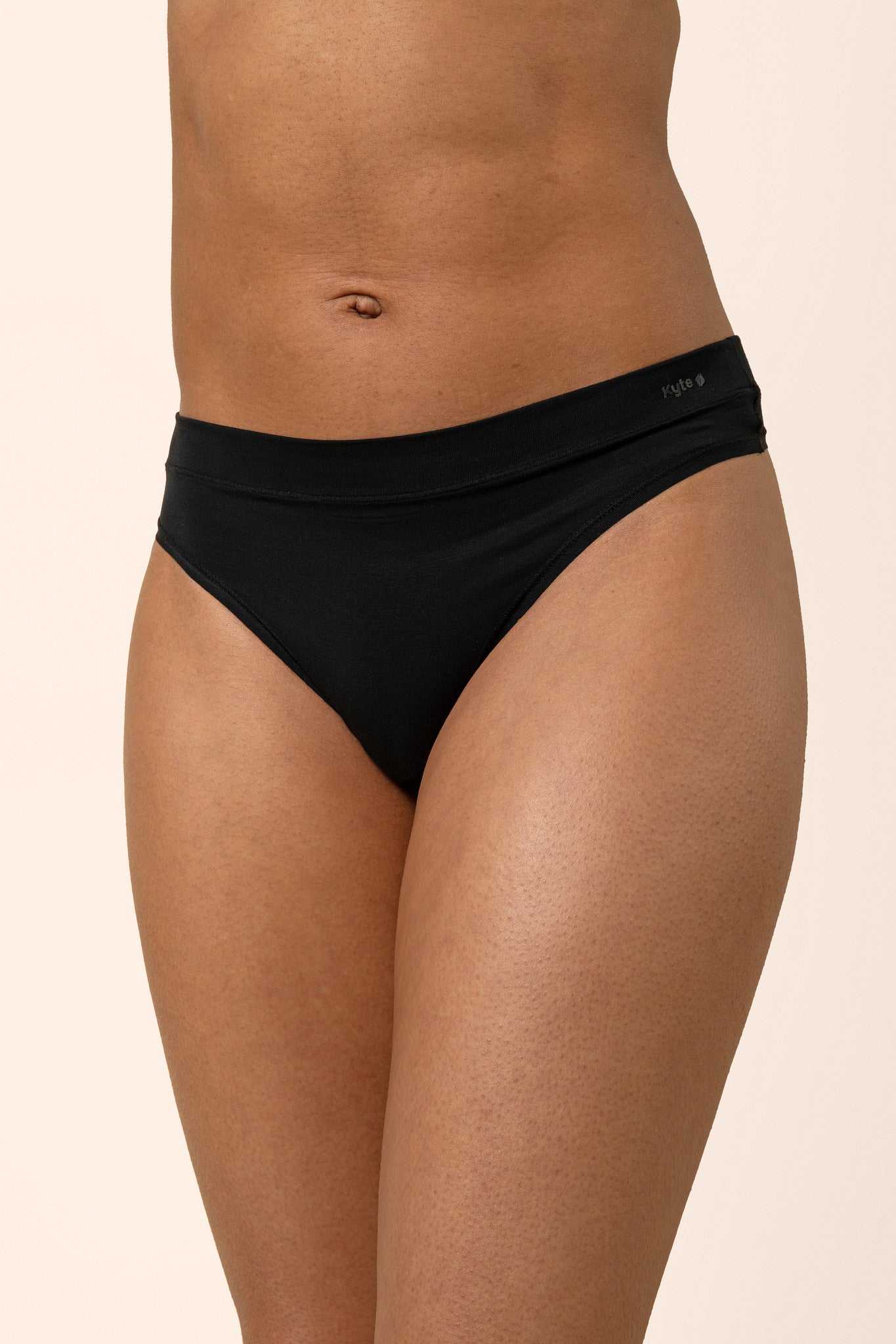 Woman wearing black thong on a beige background