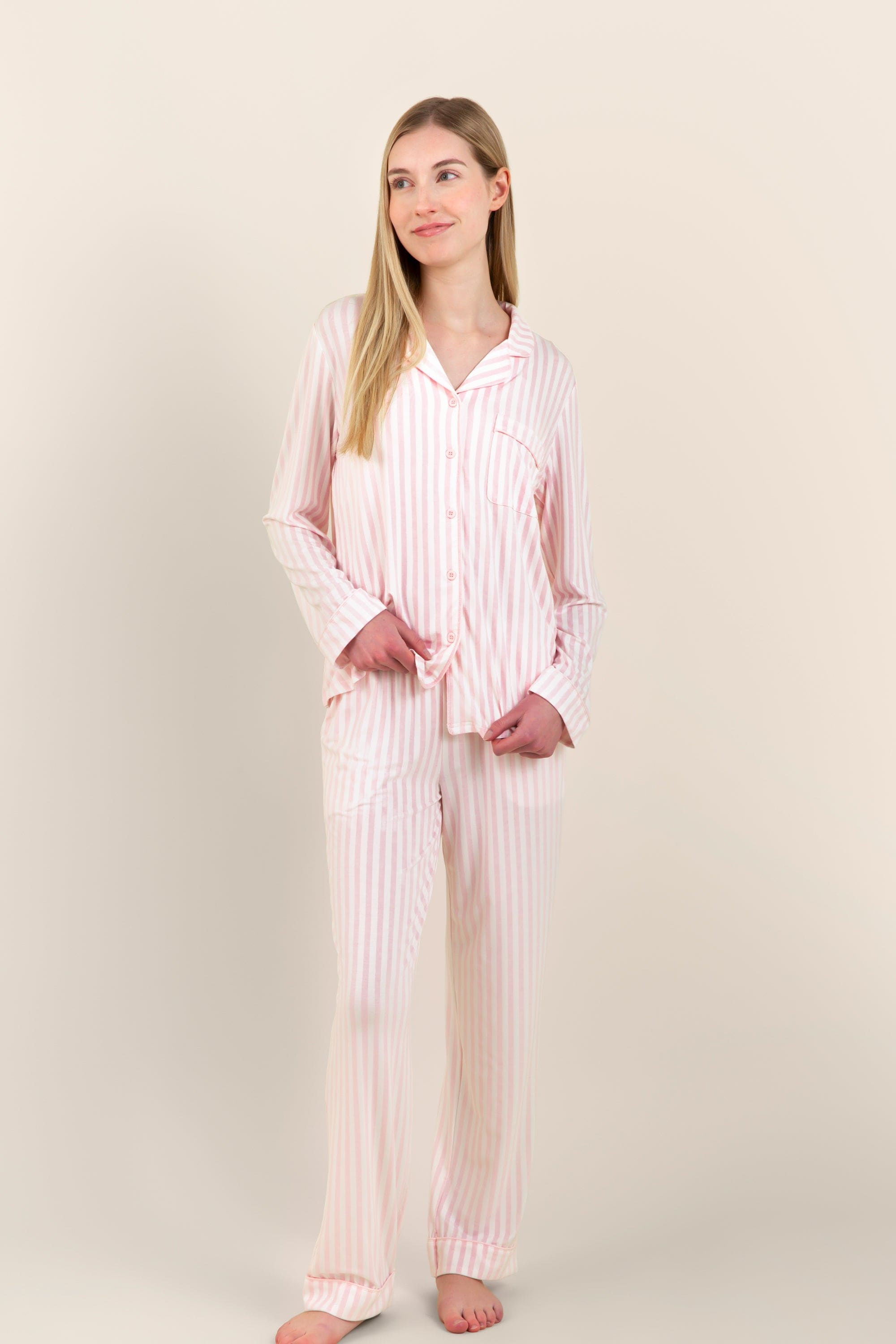 Female model standing in front of a light neutral background wearing the breathable Long-Sleeved Women's Pajama Set in Small Sakura Stripe