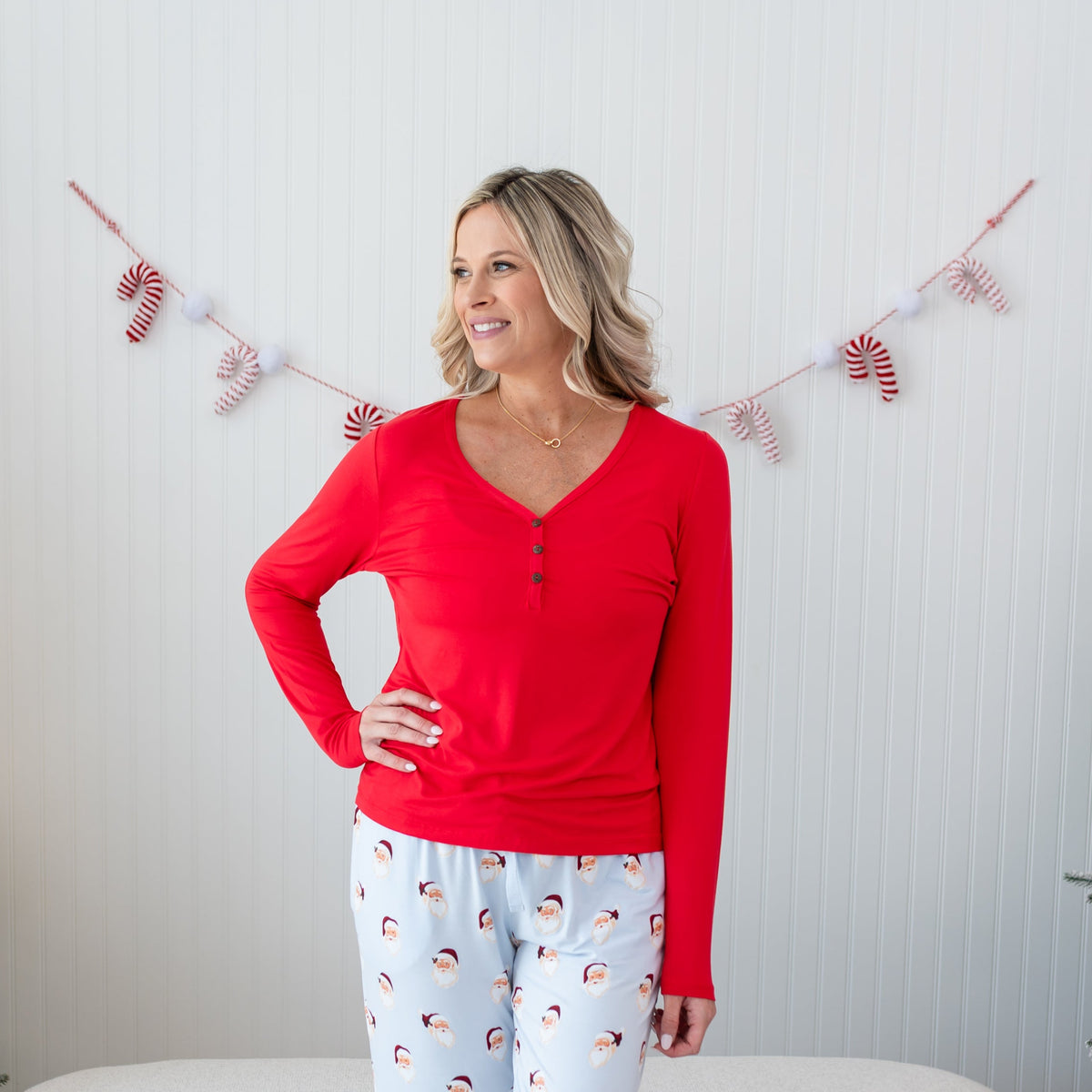 Female model standing with one hand on hip wearing the Women's Long Sleeve Henley Tee in Cardinal paired with Vintage Santa Lounge Pants