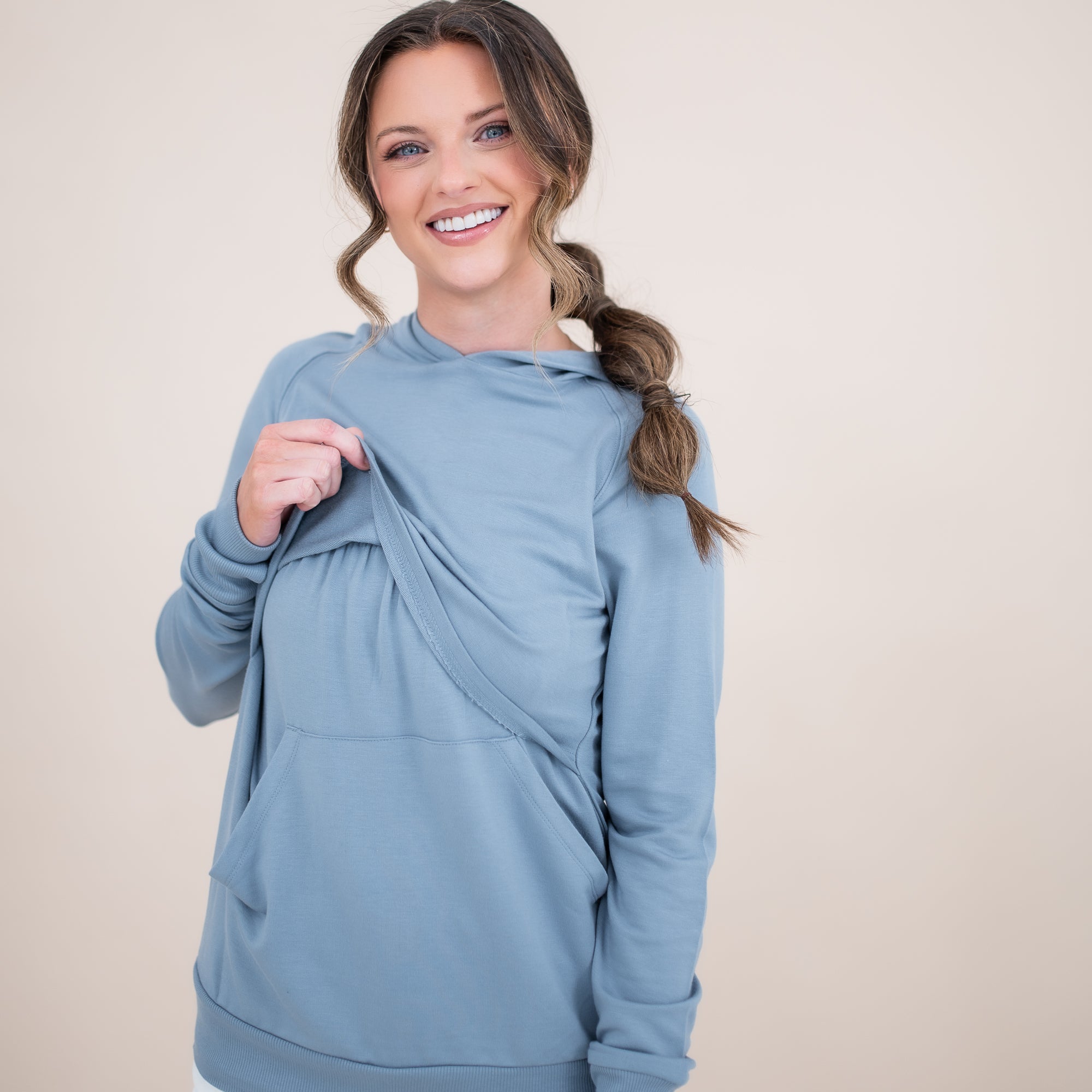 Female modeling the Women's French Terry Nursing Hoodie in Slate lifting the front fabric of the hoodie
