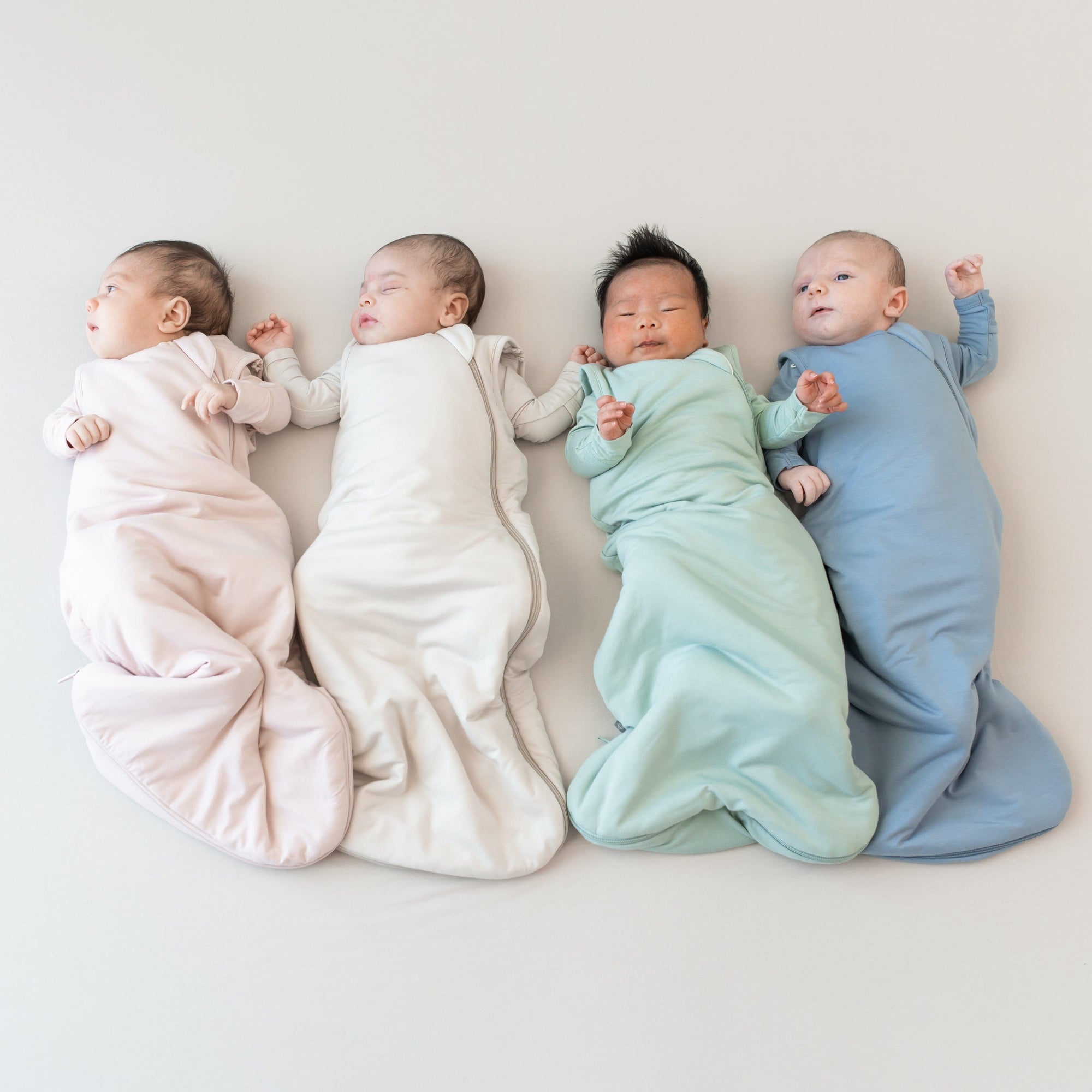 Babies in Kyte Baby Sleep Bags in blush, oat, sage and slate