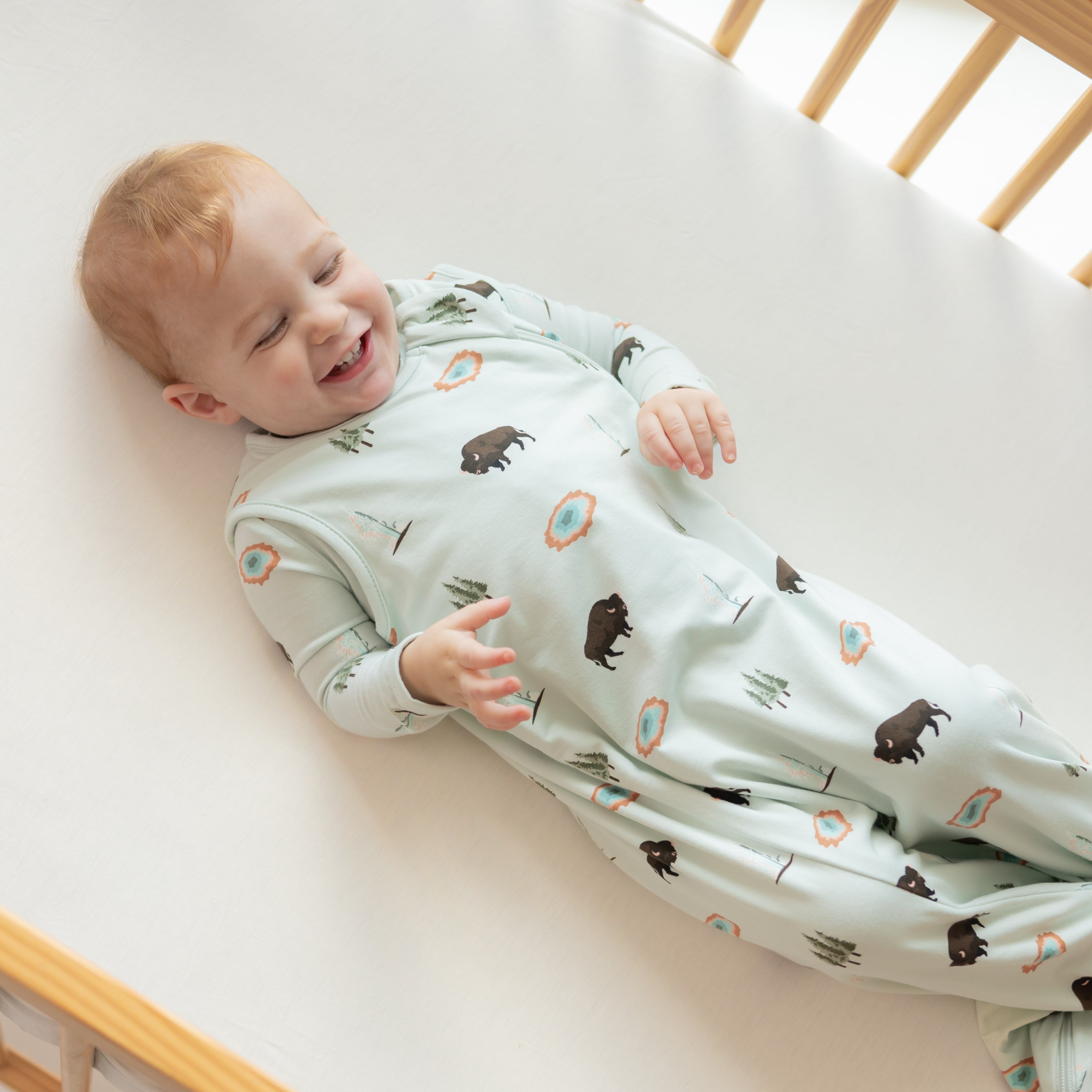 Young laughing and wearing Sleep Bag in Yellowstone 0.5 in a crib