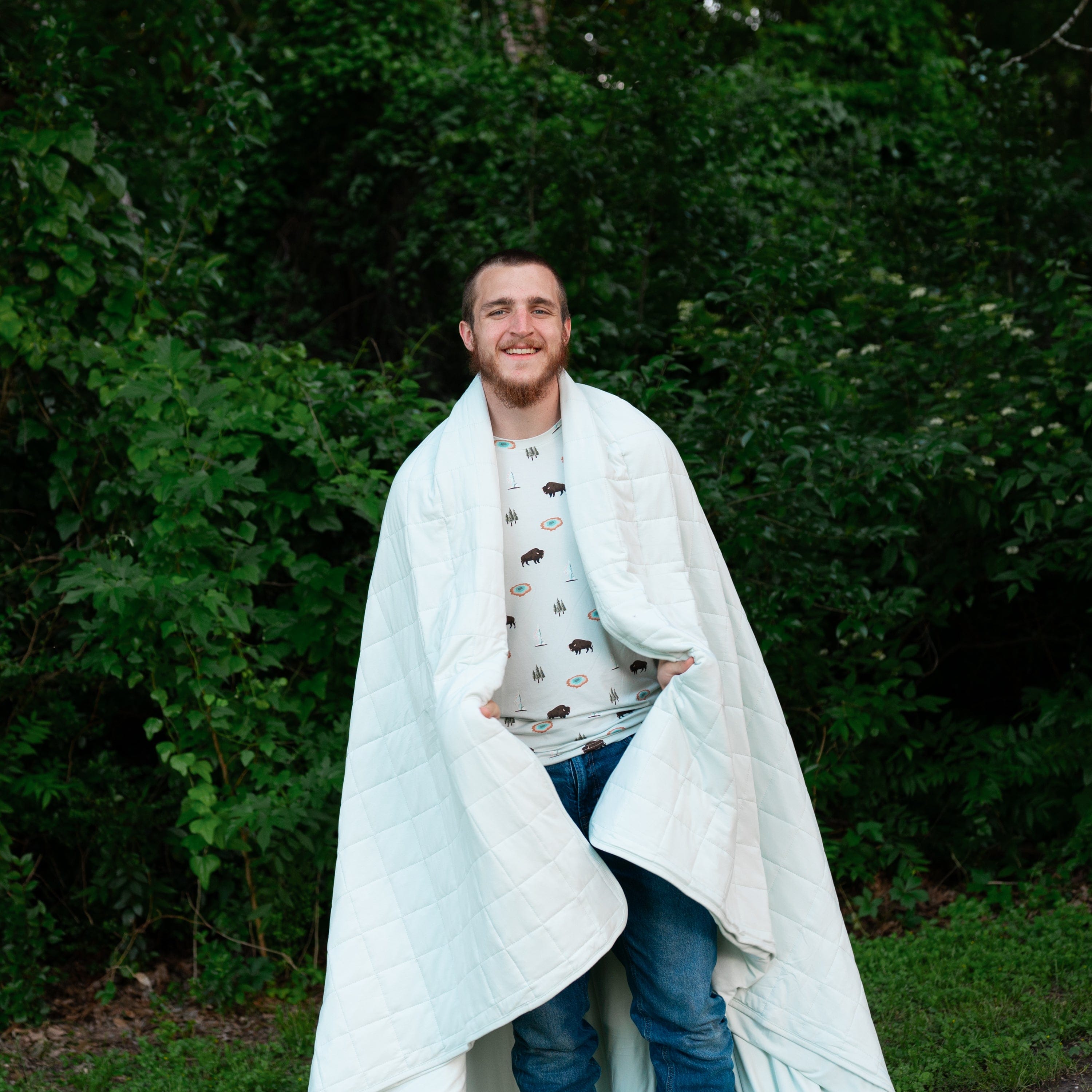 Man wearing Yellowstone crew neck warpped in Adult Quilted Blanket in Dew