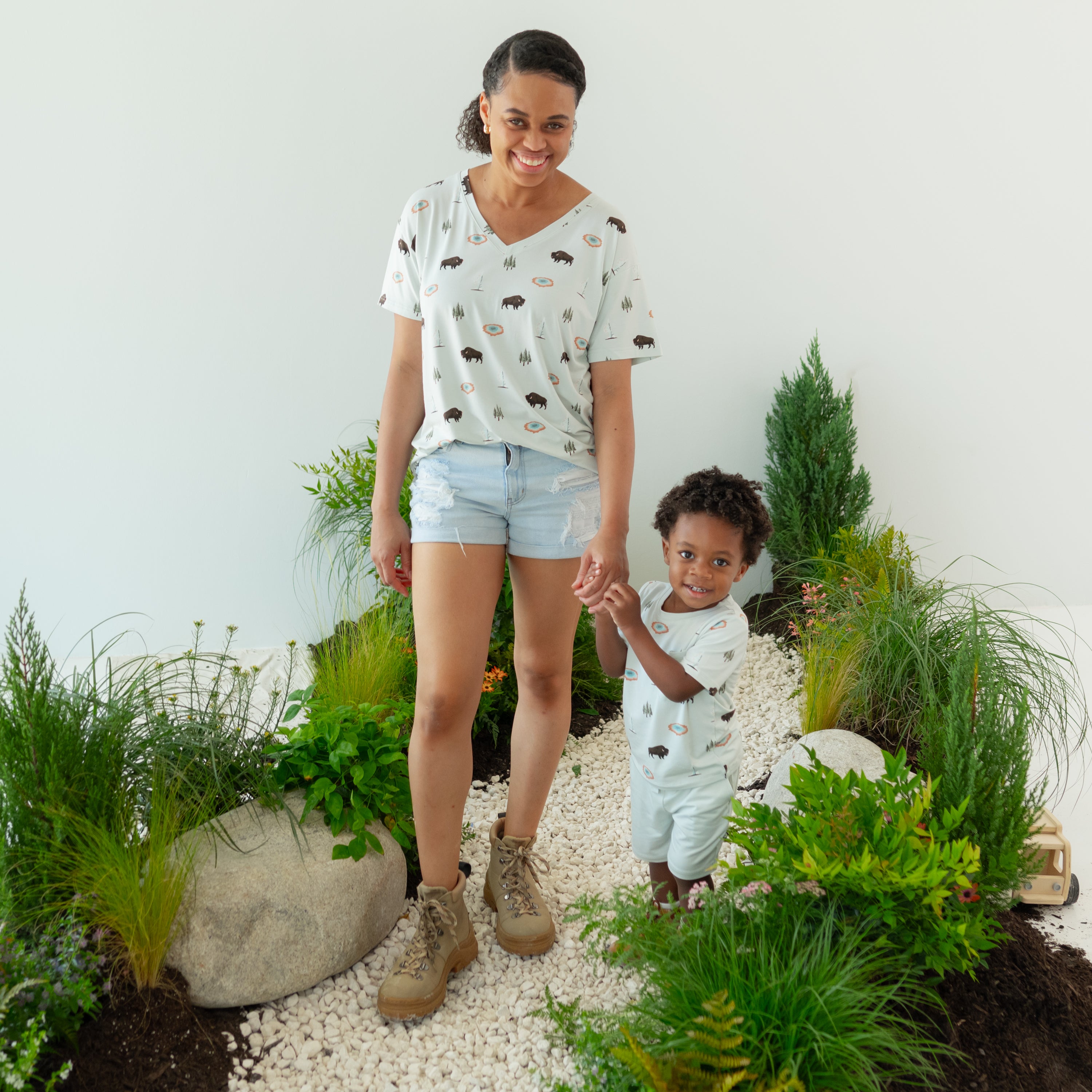 Woman wearing Women's Relaxed Fit V-Neck in Yellowstone and Toddler in matching Crew Neck Tee with nature trail backdrop