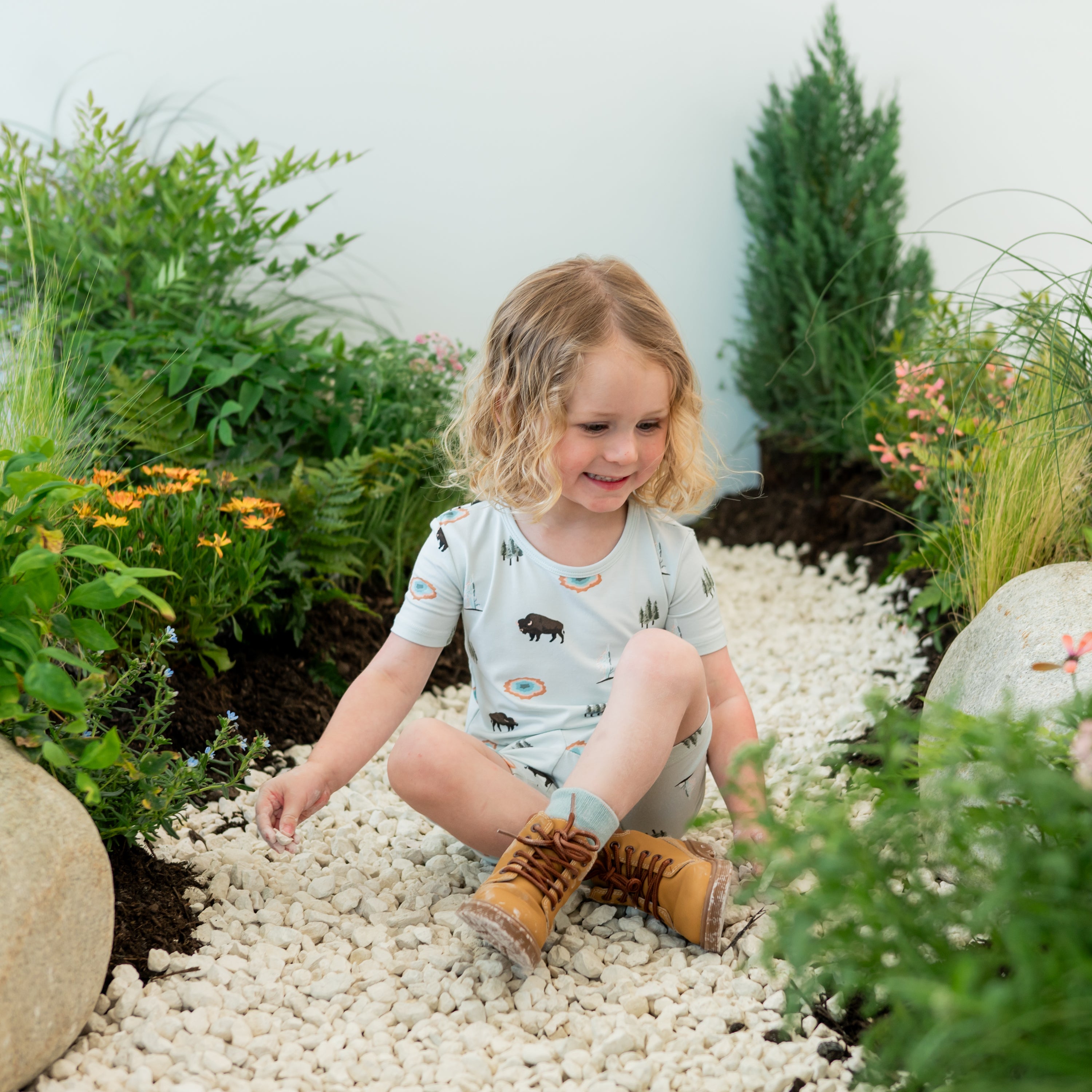 Toddler sitting modeling Short Sleeve Pajamas in Yellowstone on a nature trail backdrop