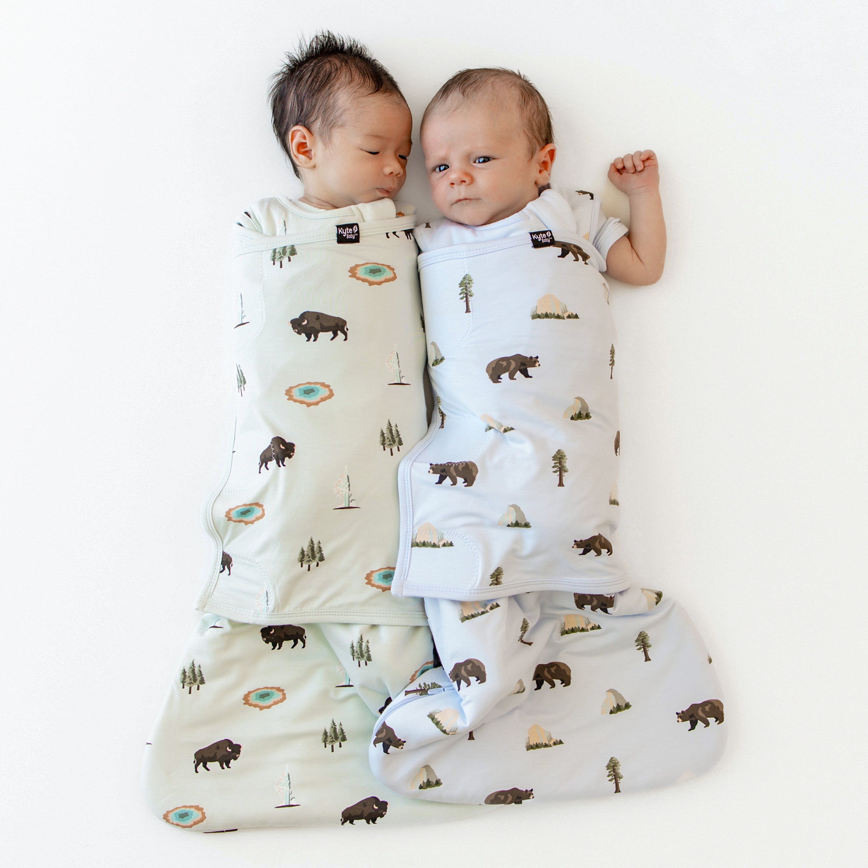 2 babies in Swaddlers in National Park Foundation x Kyte Baby collection prints Yellowstone and Yosemite