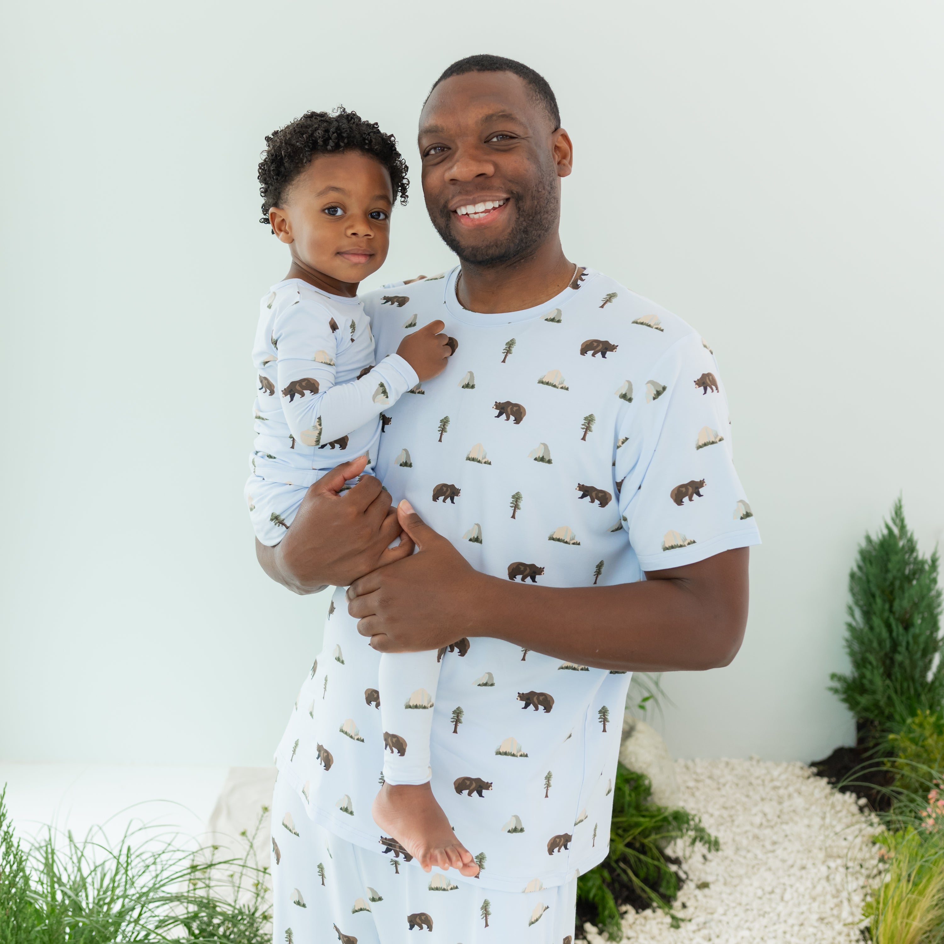 Man modeling Men's Crew Neck Tee in Yosemite holding son in Long Sleeve Pajamas