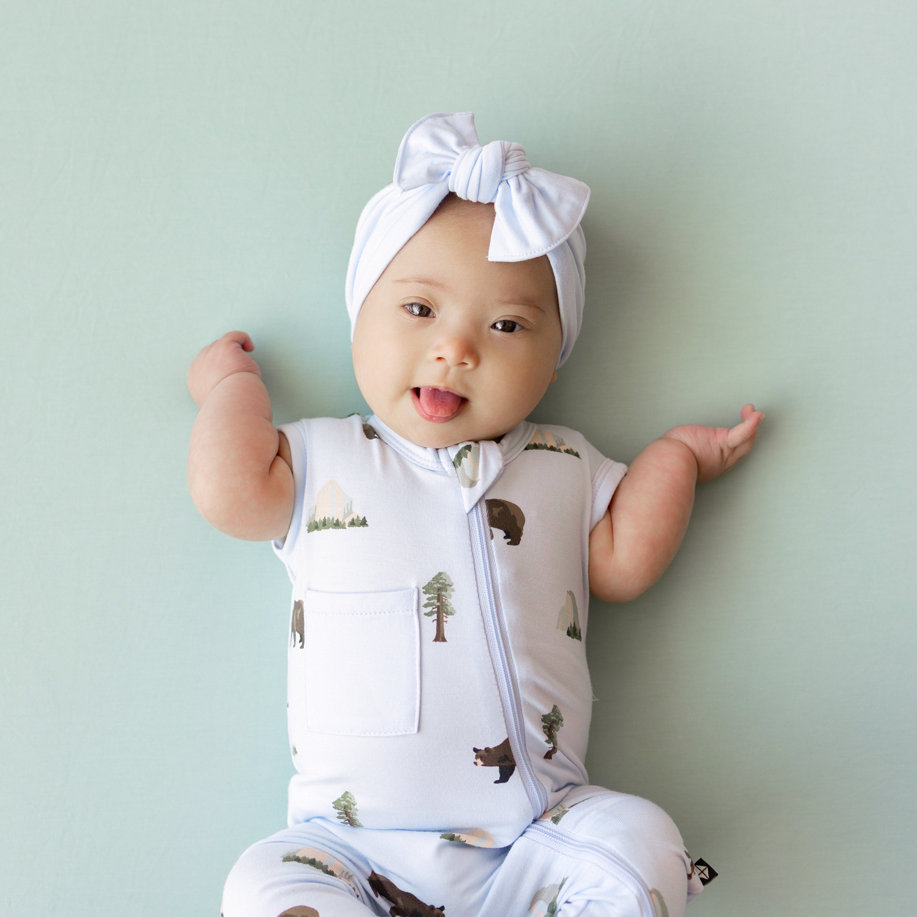 Close up of Baby wearing Zippered Sleeveless Romper in Yosemite with Mist Bow