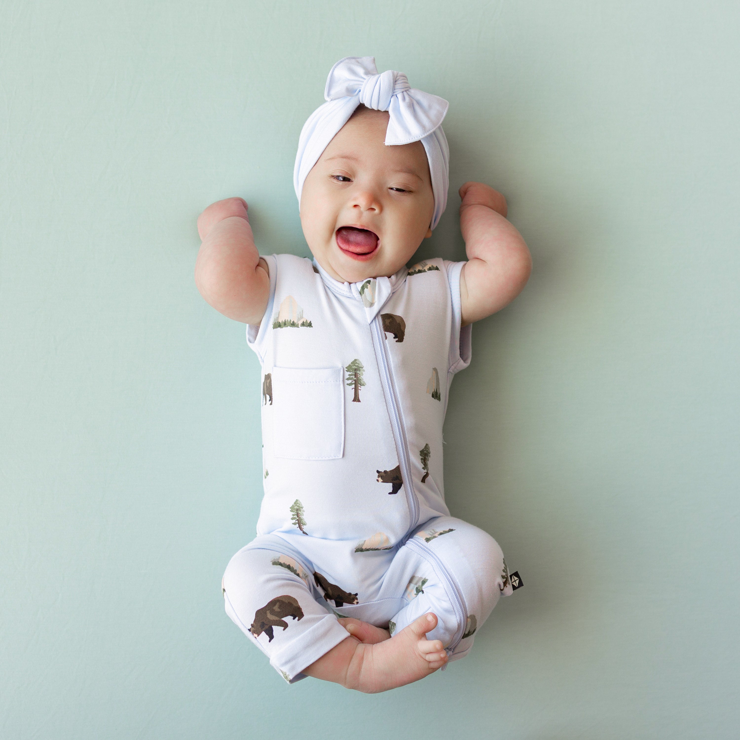 Baby wearing Zippered Sleeveless Romper in Yosemite with Mist Bow