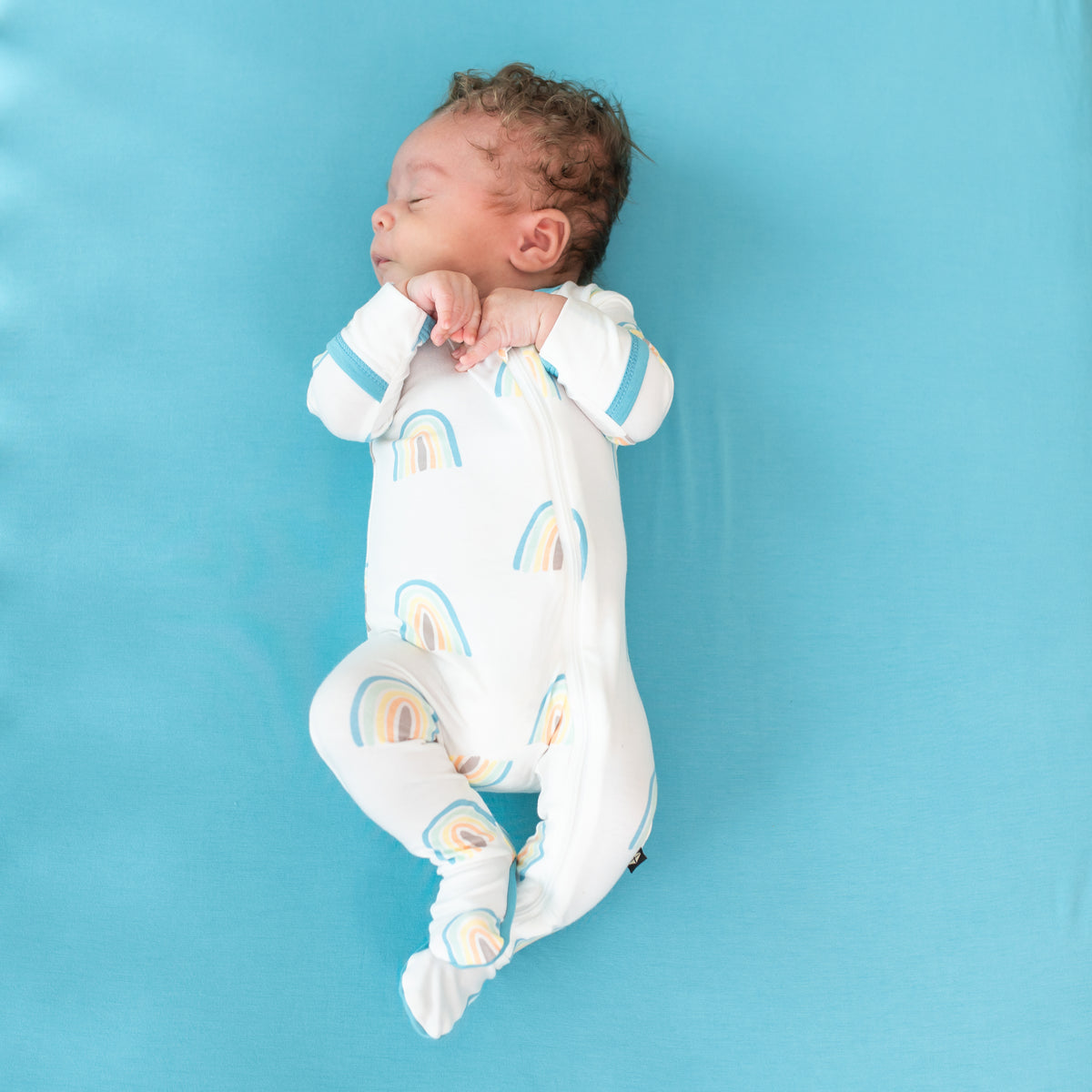 Baby sleeping in Zippered Footie in Makai Rainbow