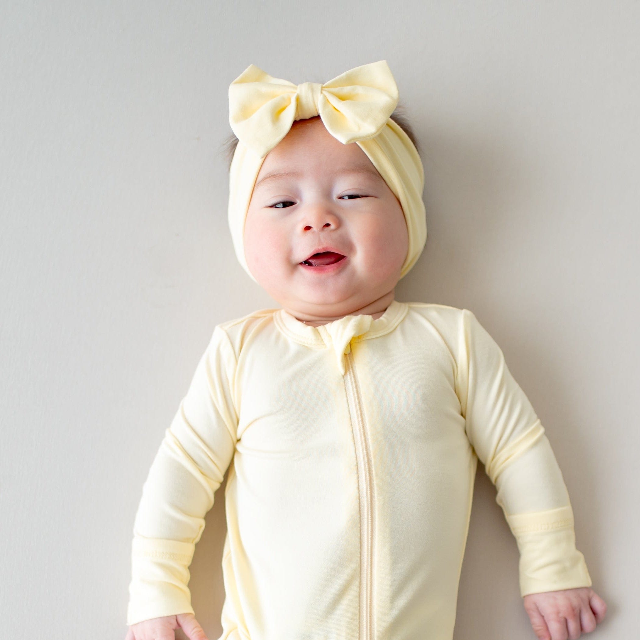 Baby wearing a yellow bow headband and matching outfit