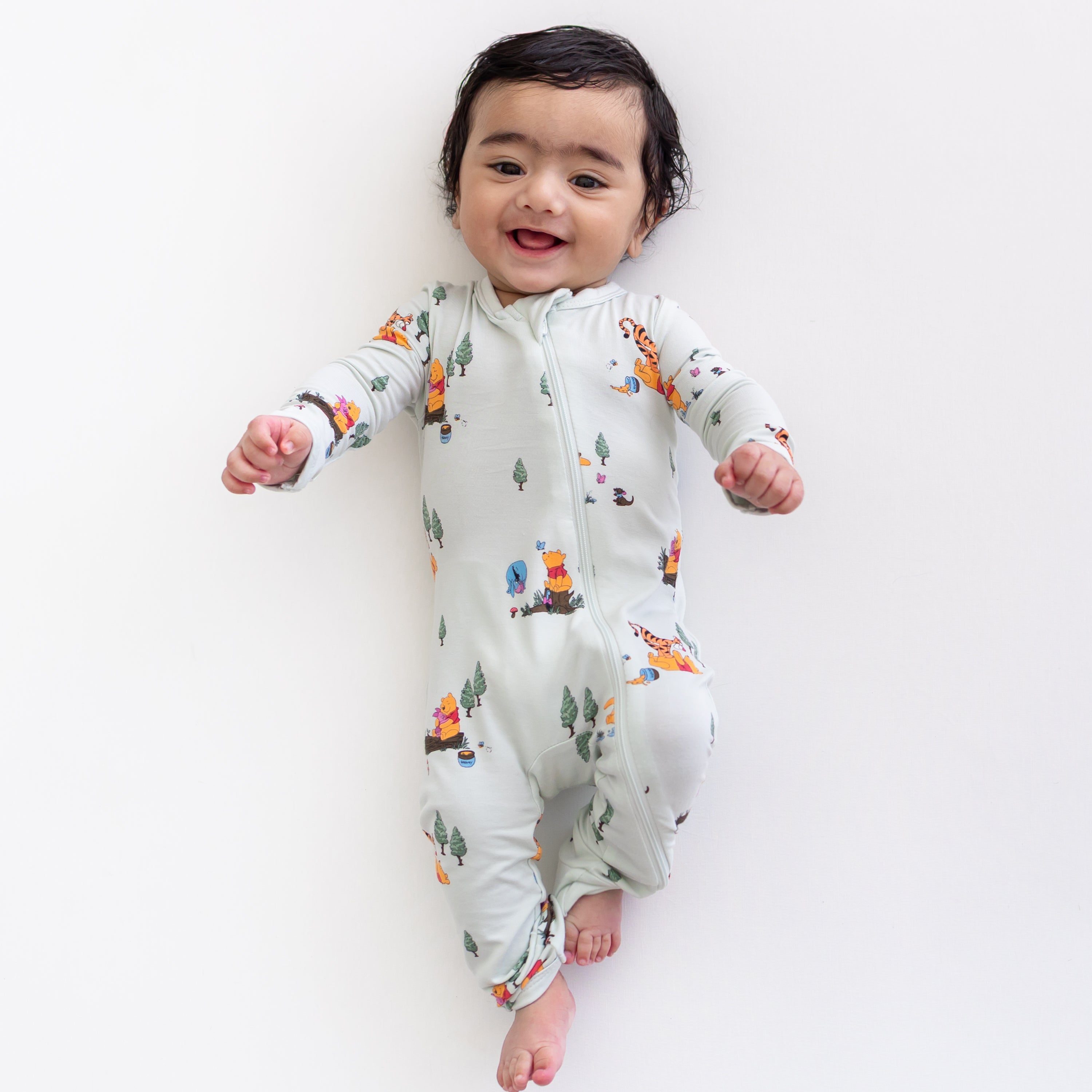 Smiling infant wearing the Zippered Romper in Winnie the Pooh Hundred Acre Wood