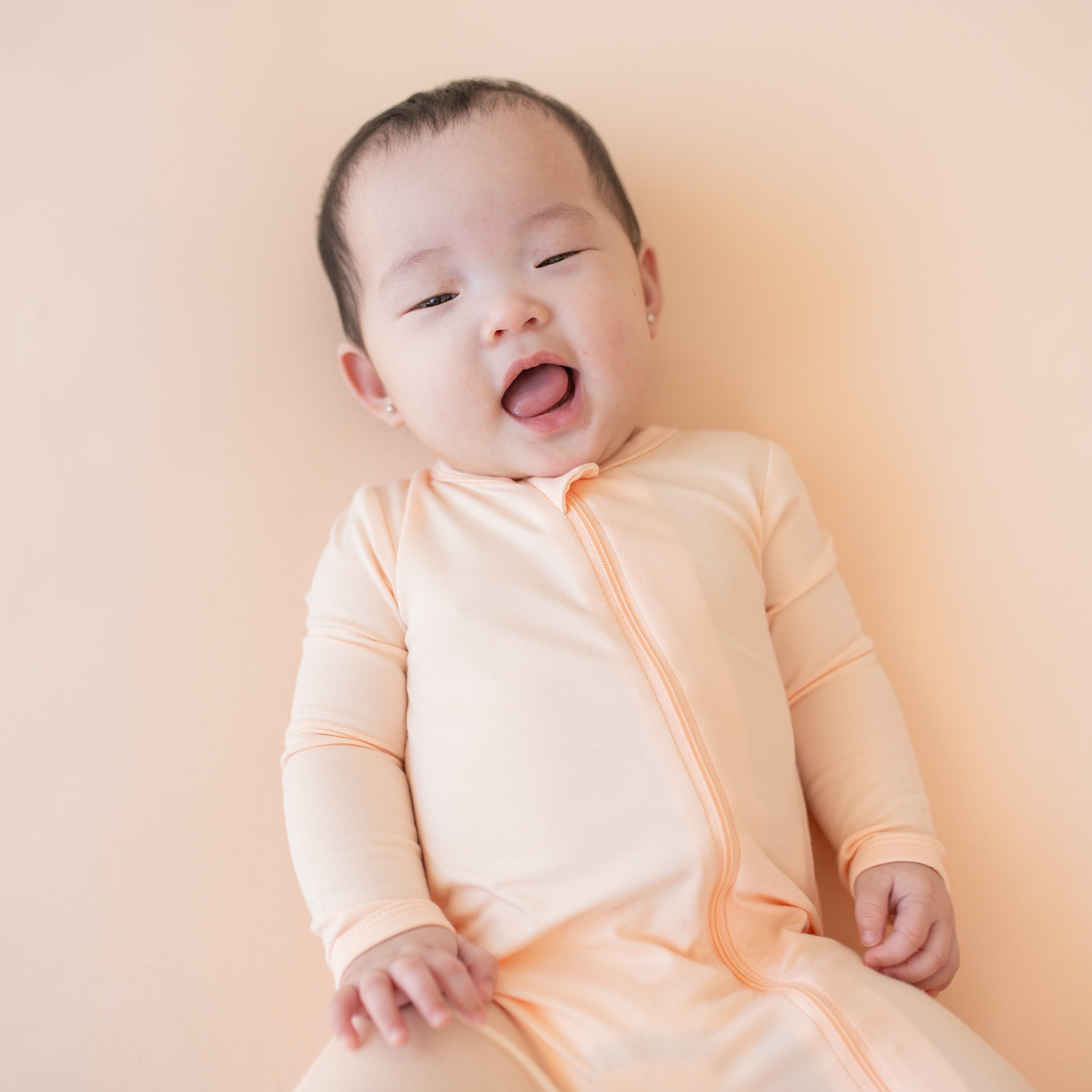 Smiling baby wearing the Zippered Romper in Canyon