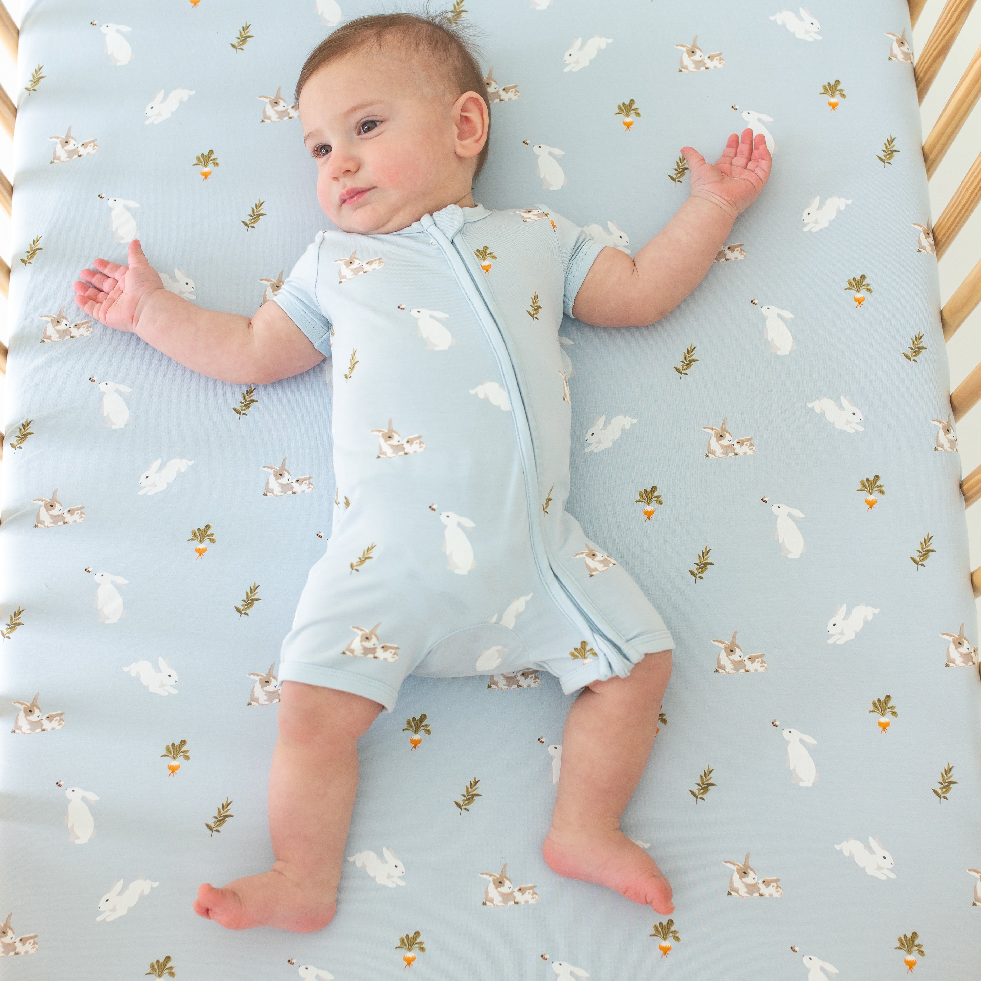 Infant wearing Kyte Baby Zippered Shortall Romper with dual zipper in Ice Rabbit