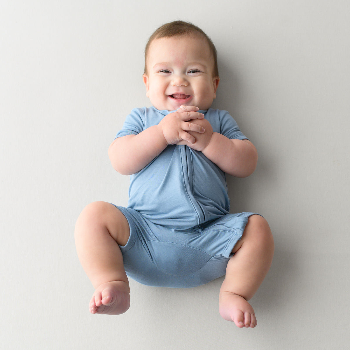 Smiling baby modeling Zipper Shortall Romper in Slate