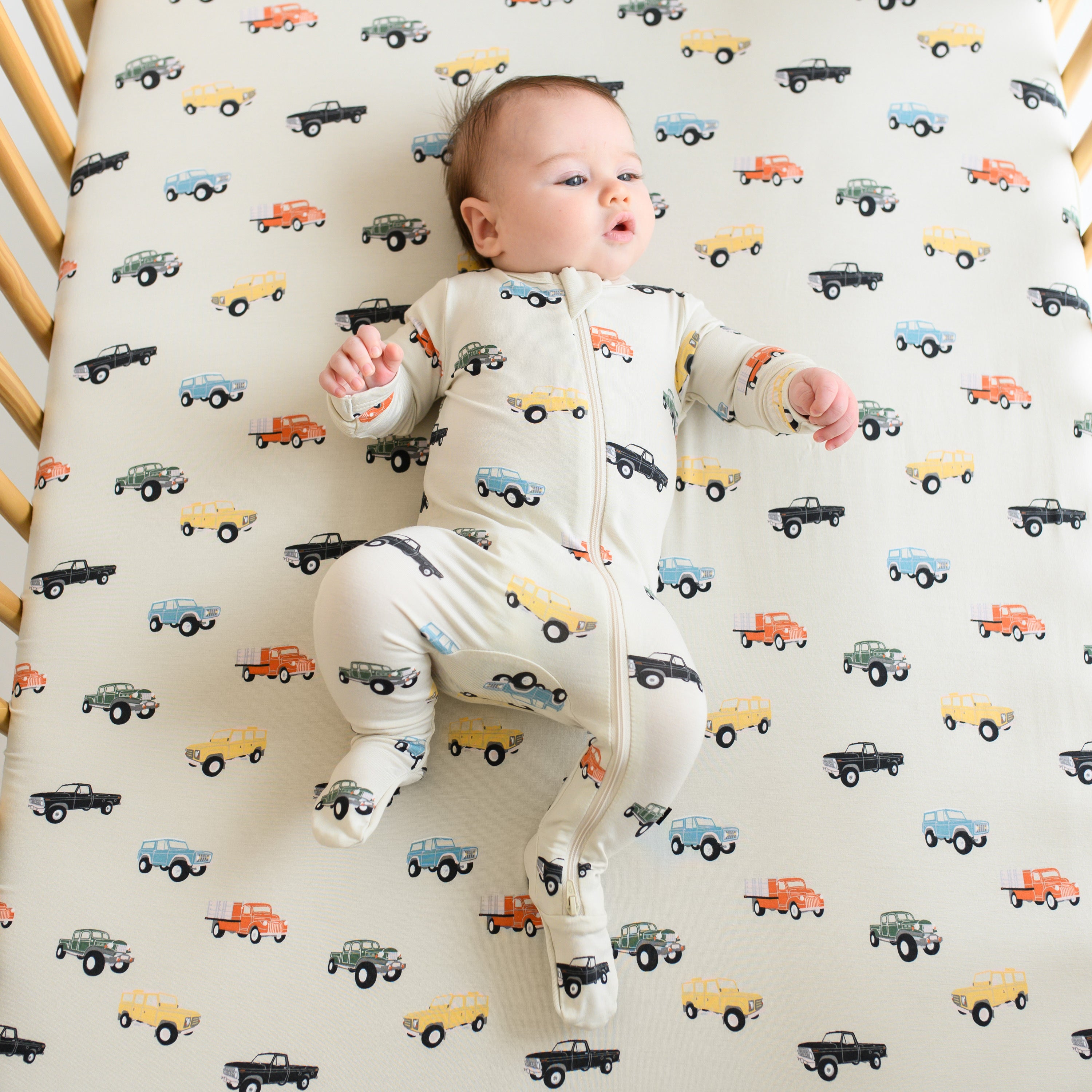 Baby laying on Crib Sheet in Vintage Truck in matching footie pajamas