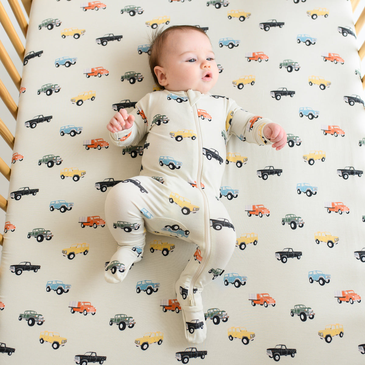Baby laying on Crib Sheet in Vintage Truck in matching footie pajamas